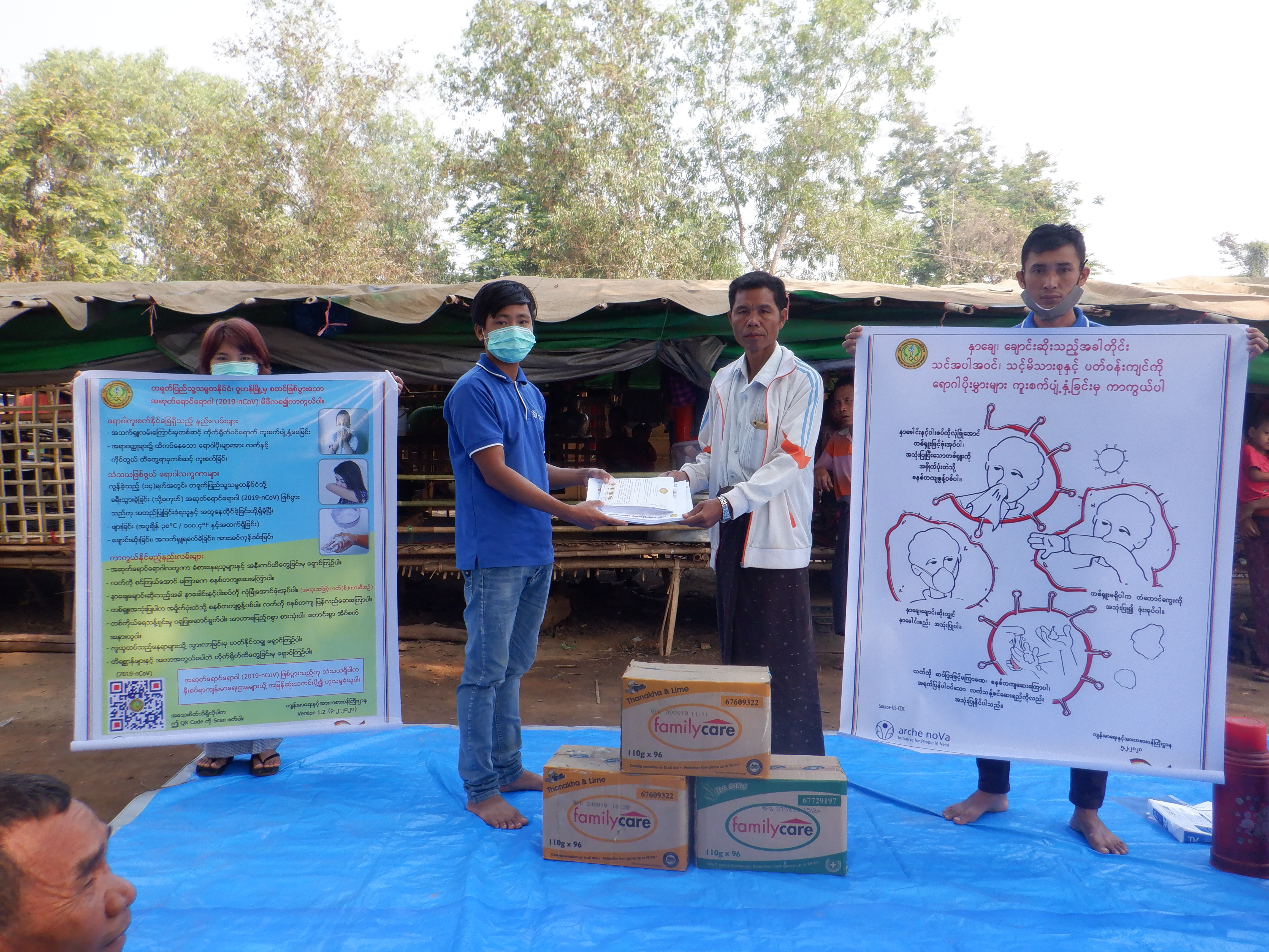 Menschen aus Myanmar zeigen Päckchen und Plakate zur VErteilung