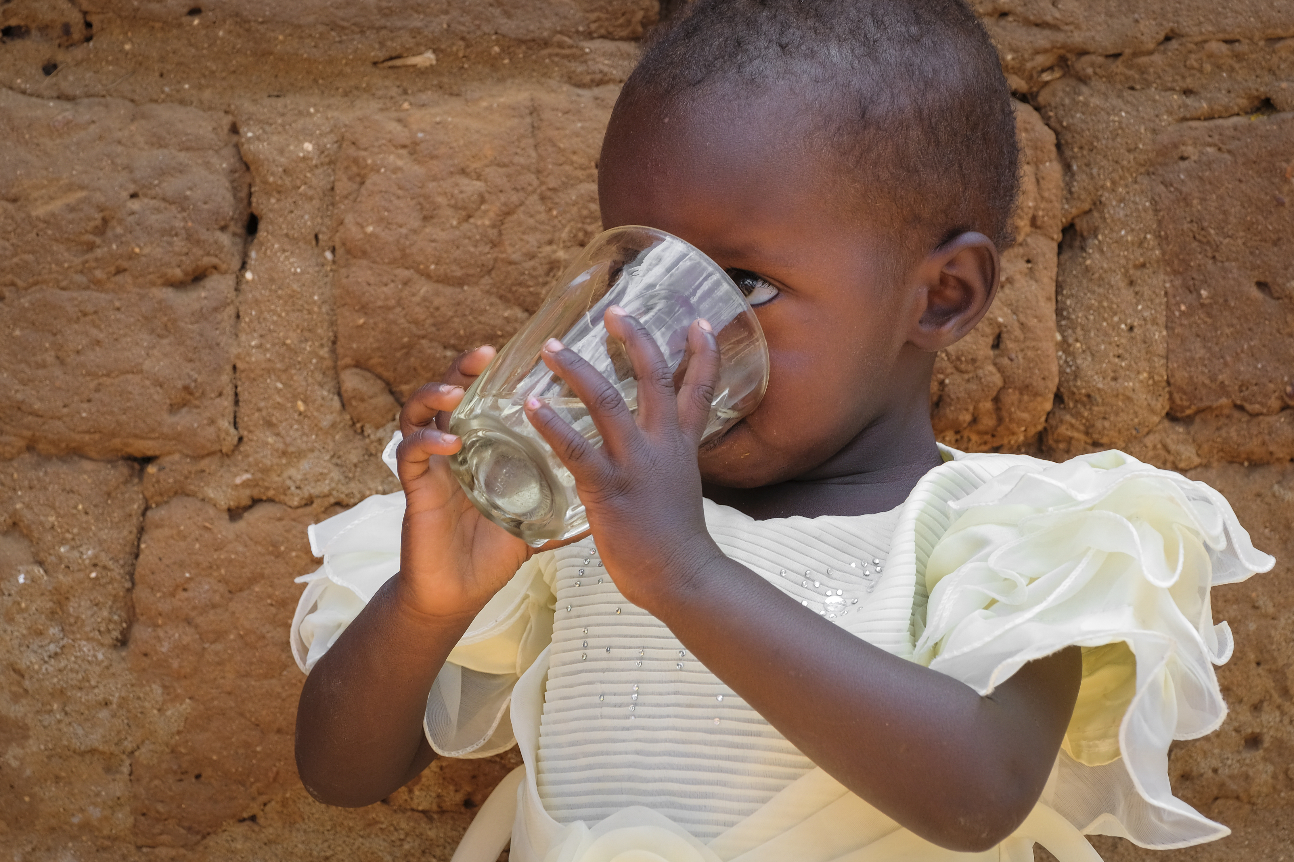 Ein Kleinkind trinkt aus einem Glas Wasser