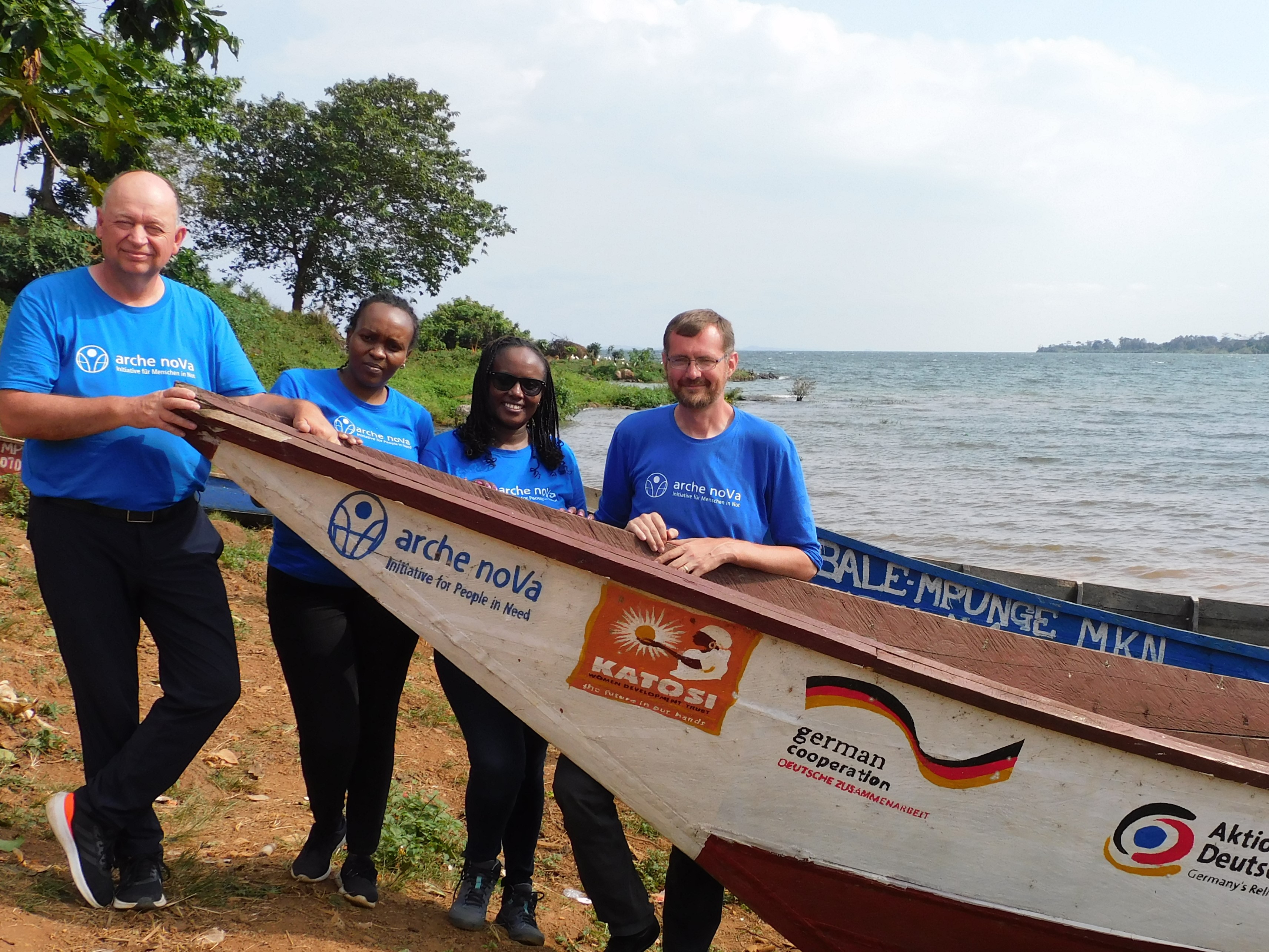 The picture shows the new Managing Director of arche noVa, Dr. Jens Ola (left). Together with Mathias Anderson (right), Sophia Maina (Regional MEAL/Reporting Officer, 2nd from left) and Juliet Muthiani (Program Officer), he is standing behind a fishing boat that arche noVa provided to the fishing community of Mbale in Uganda.