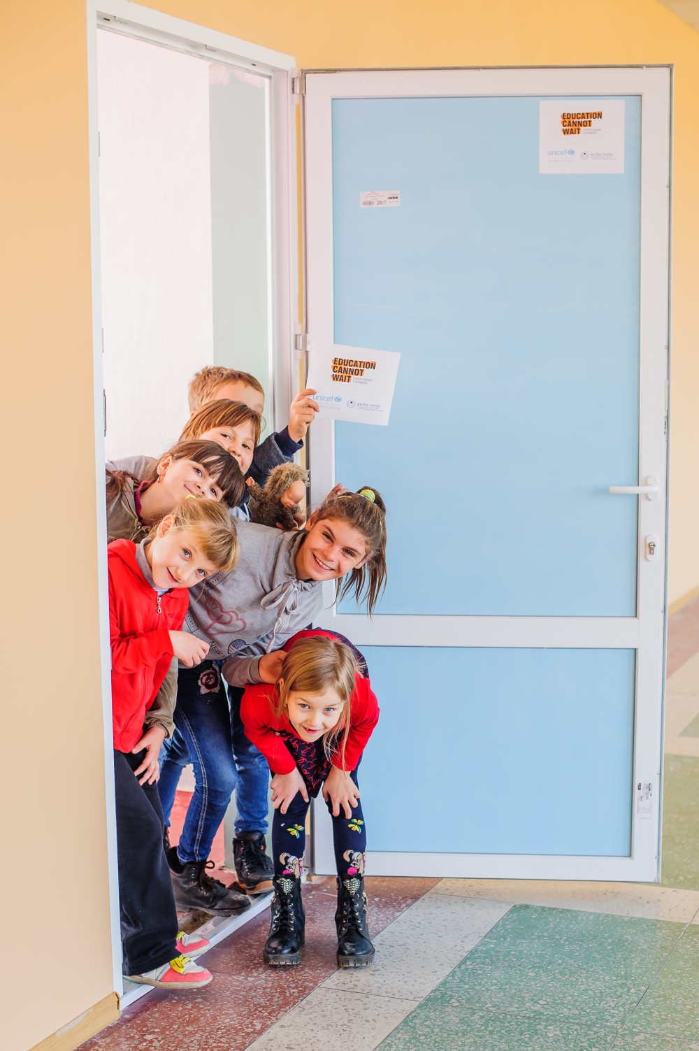 Mehrere Kinder gucken lächelnd zur Tür hinein