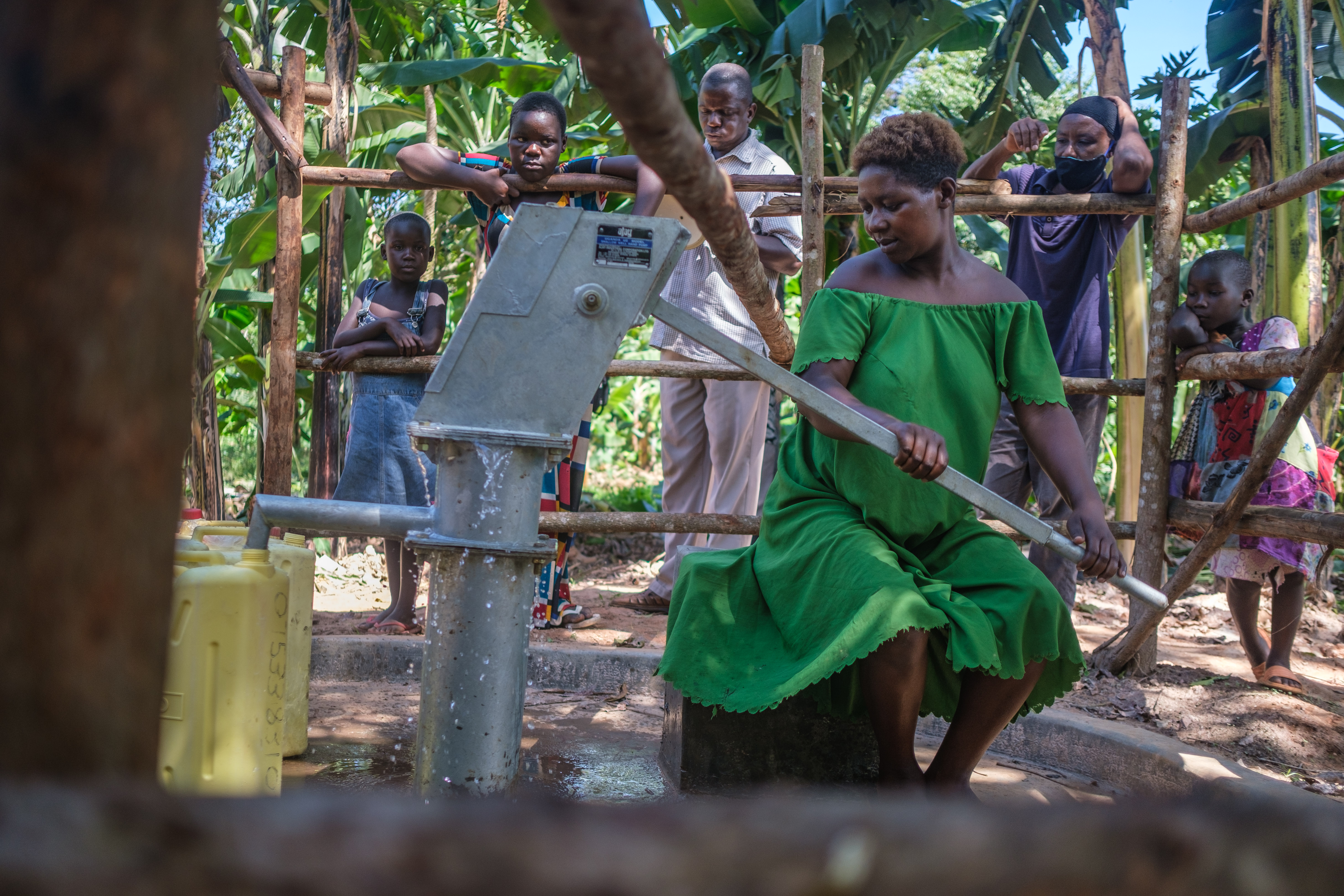 eine Frau pumpt Wasser an einer Handpumpe