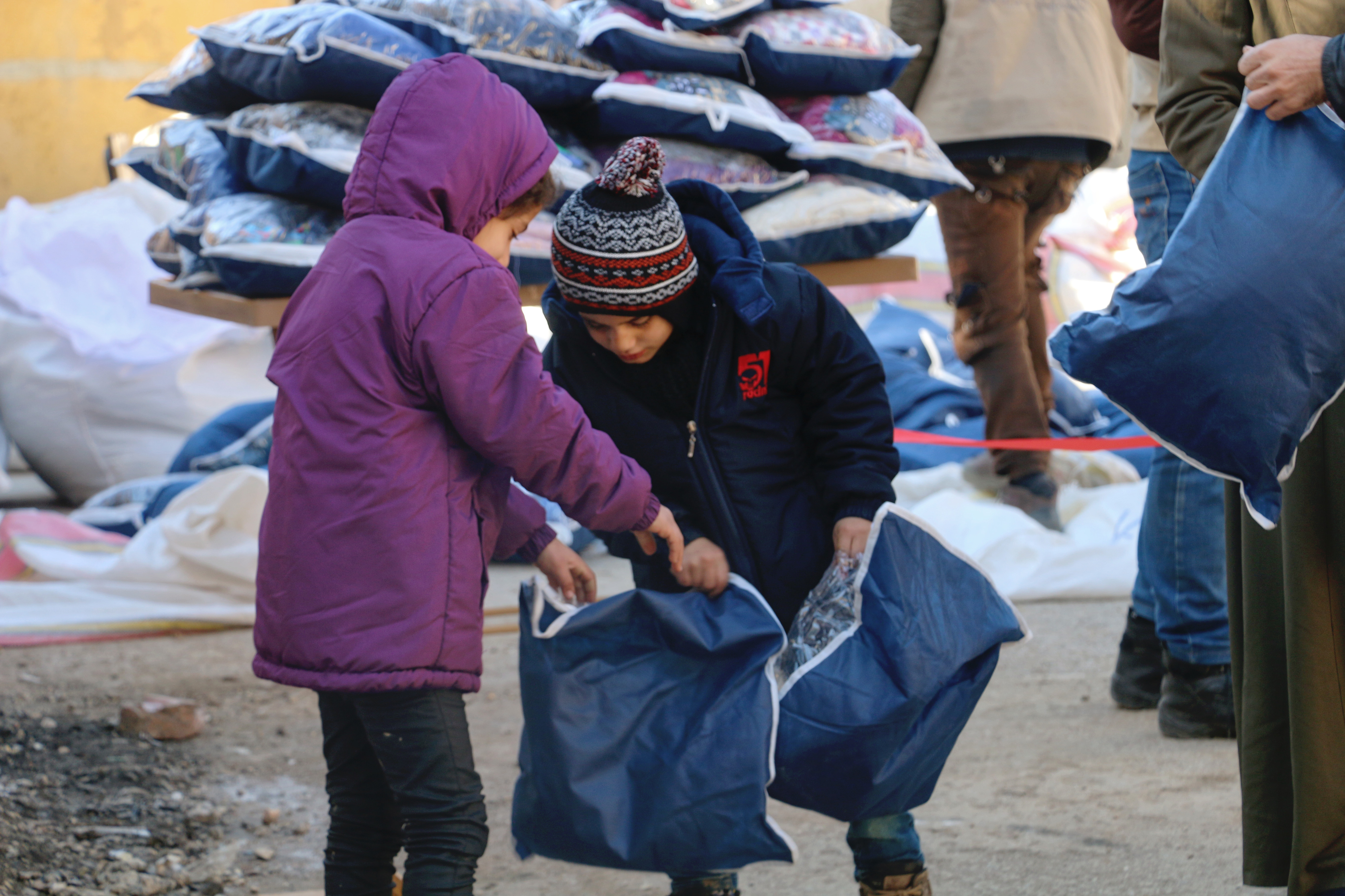 Zwei Kinder schauen in Beutel, die sie im Rahmen der Winterhilfe erhalten haben