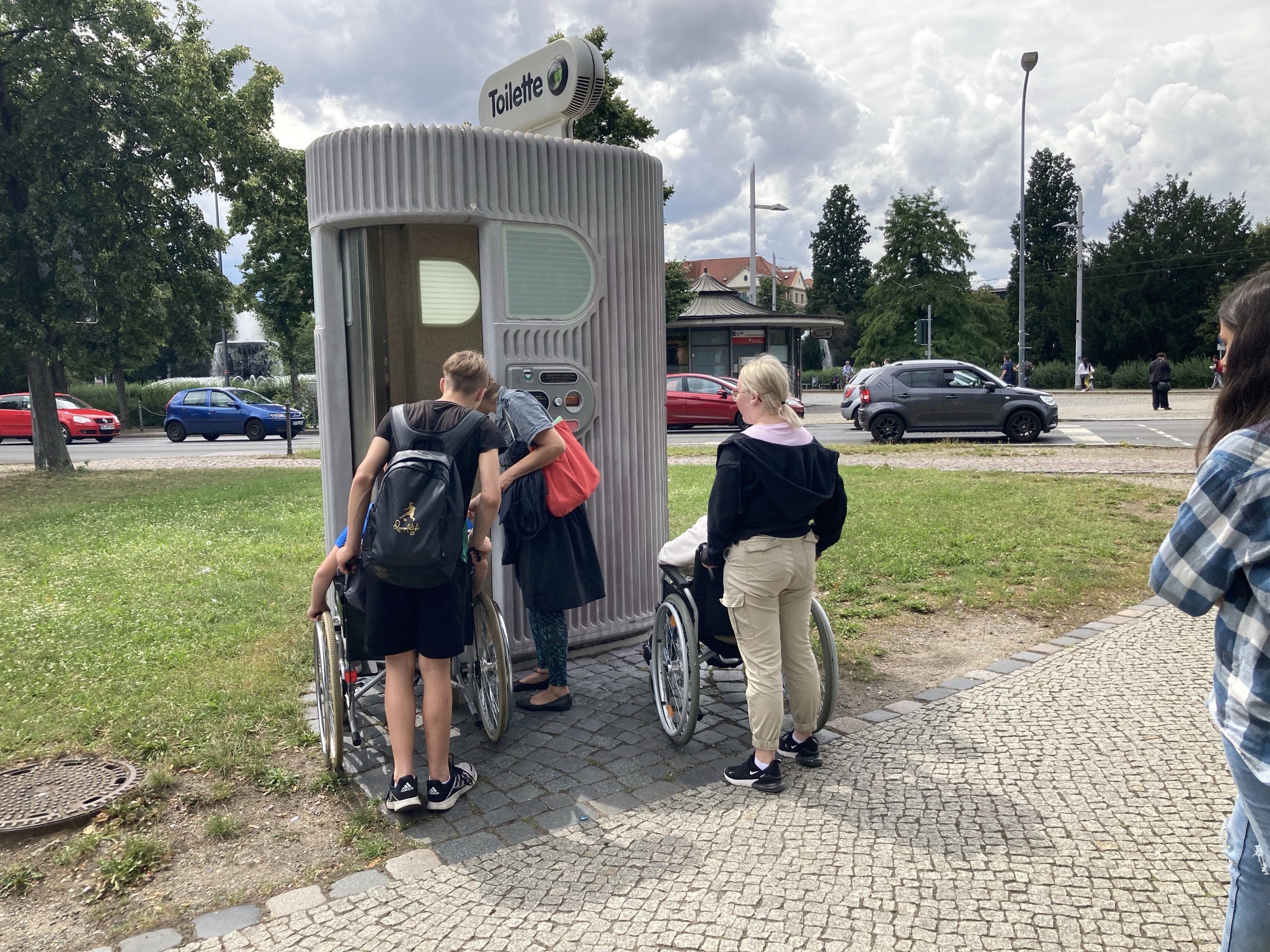 Jugendliche in Rollstühlen vor öffentlicher Toilette