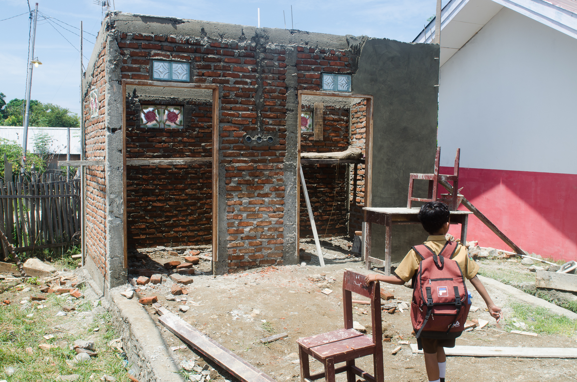 ein Schulkind läuft zu einem Toilettenhaus, das gerade gebaut wird