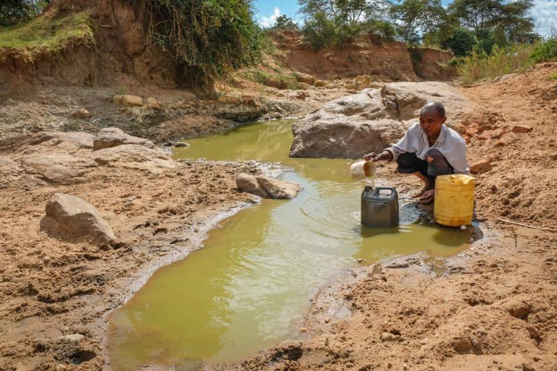 Man scoops water from a puddle