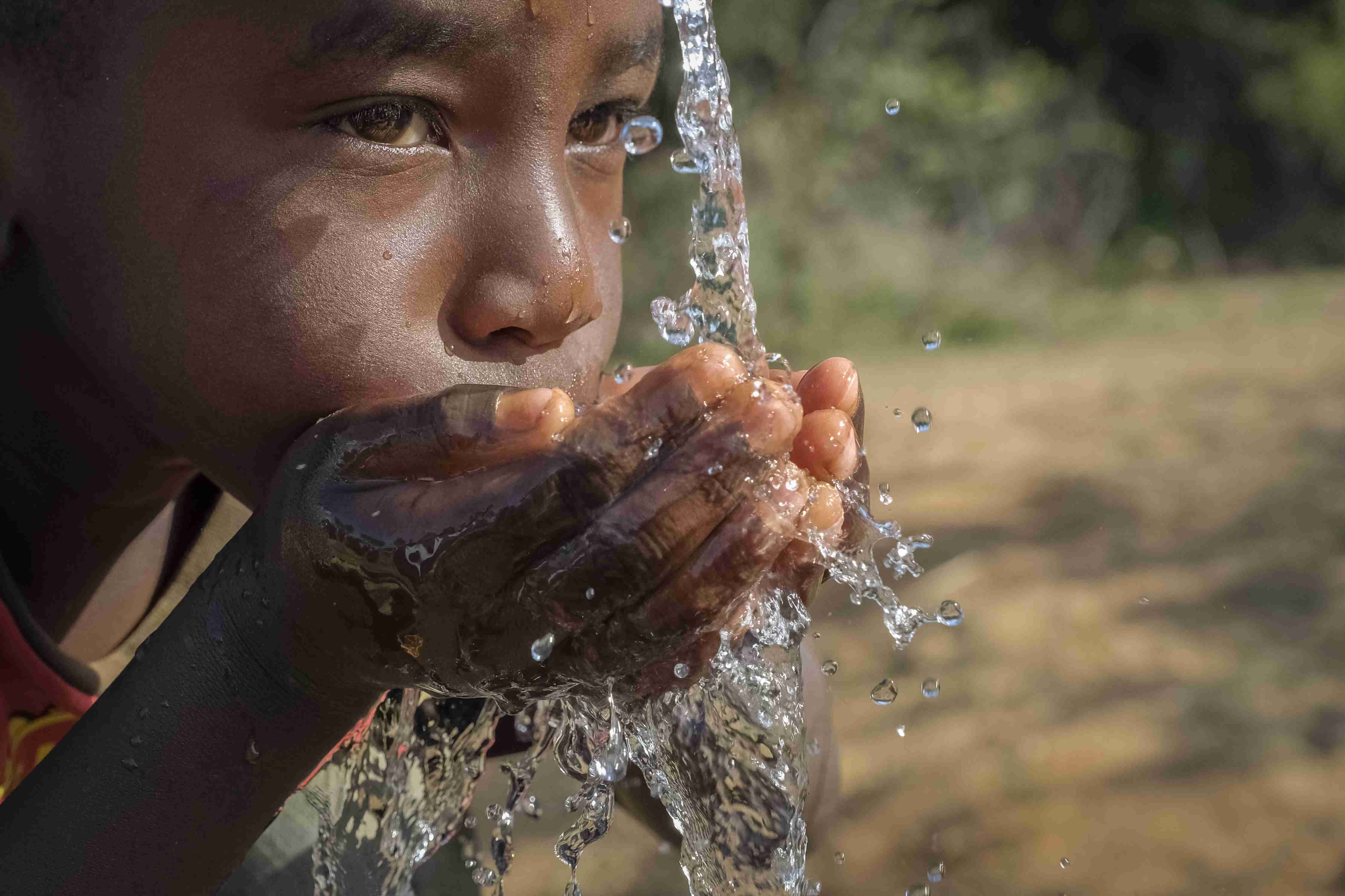 Kind trinkt Wasser aus den Händen