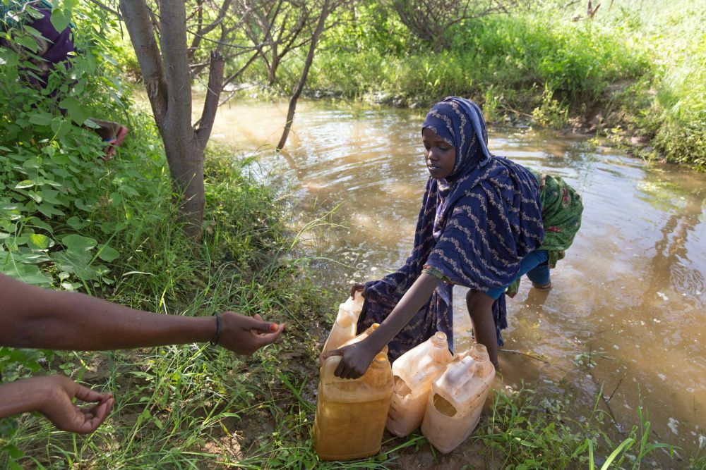 Frau holt Wasser aus Fluss