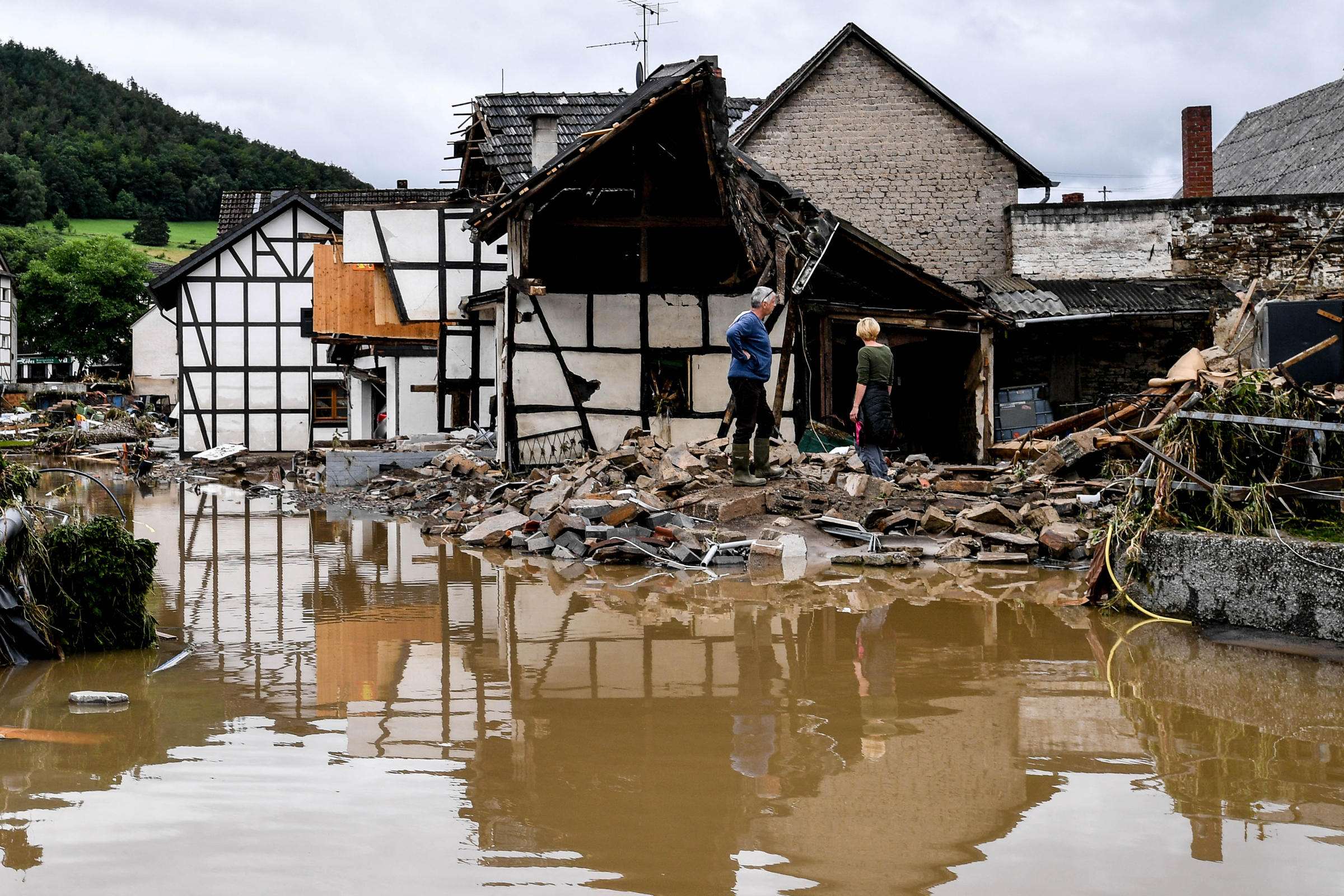 Hochwasserkatastrophe in Deutschland - Zwei Personen vor zerstörtem Haus
