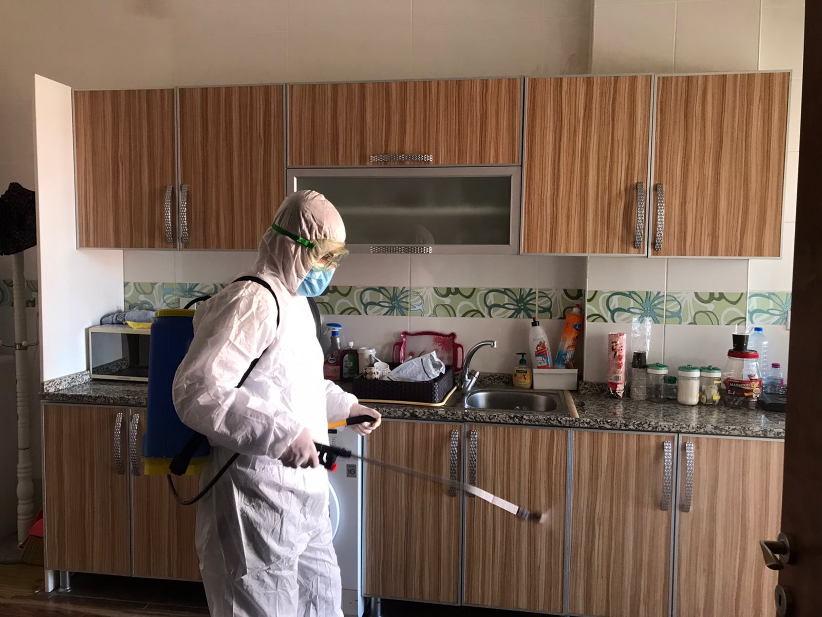 Mann in Schutzkleidung sprüht eine Küchenzeile ein