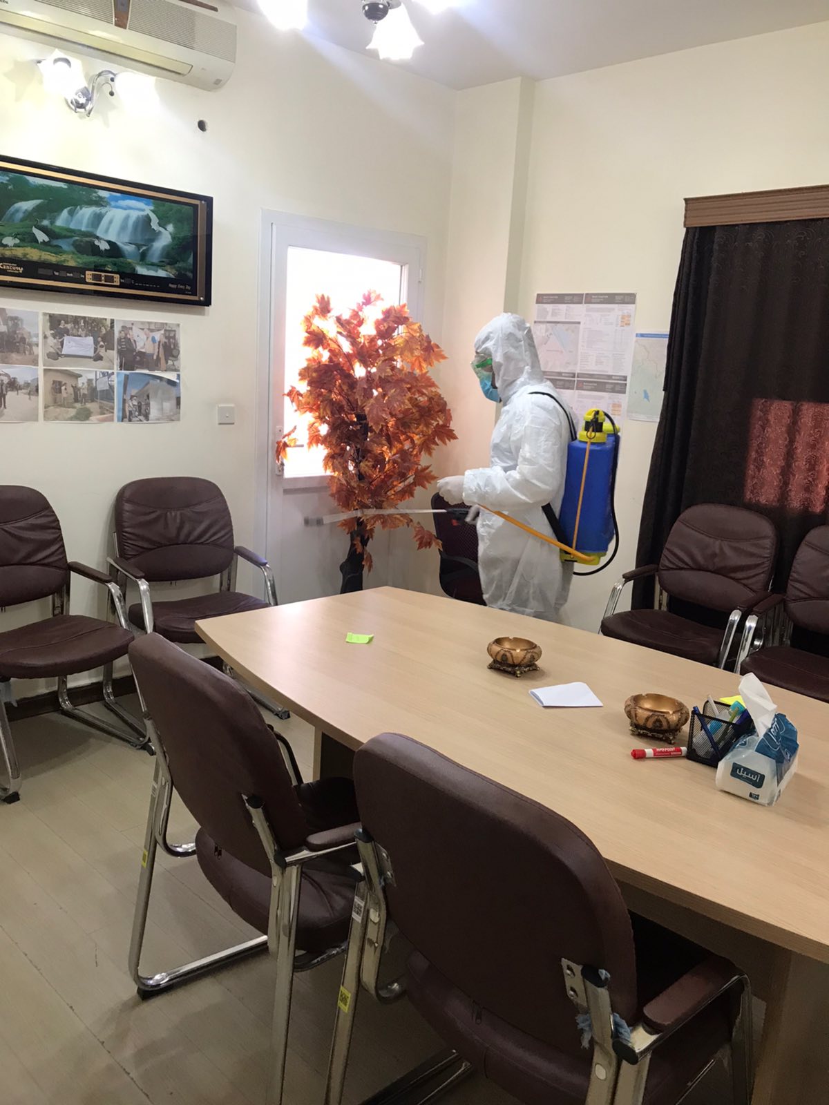 Mann in Schutzkleidung sprüht einen Büroraum mit Desinfektionsmittel ein