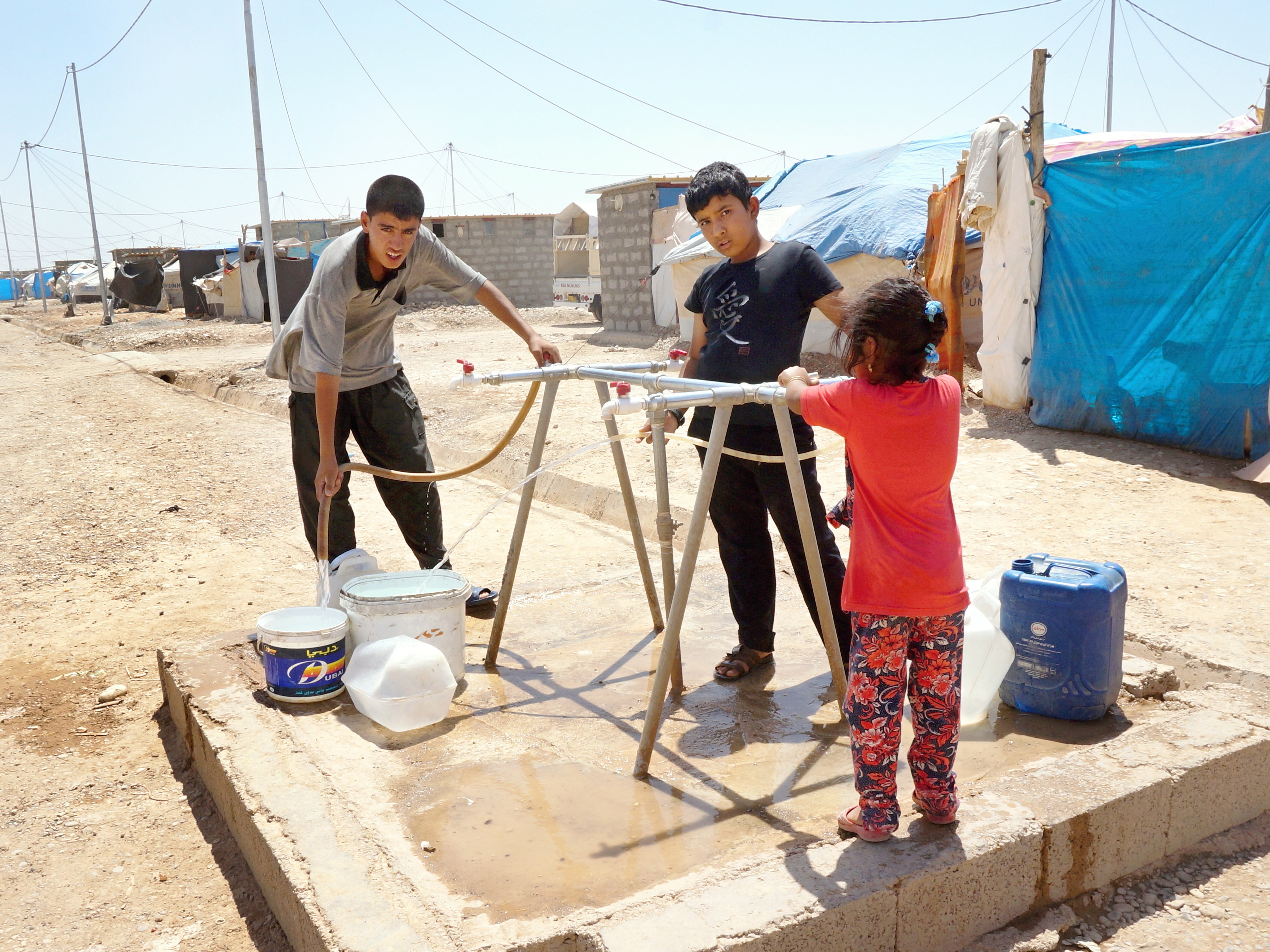 Kinder füllen Kanister und Eimer an der Wasserabgabestelle im Flüchtlingscamp