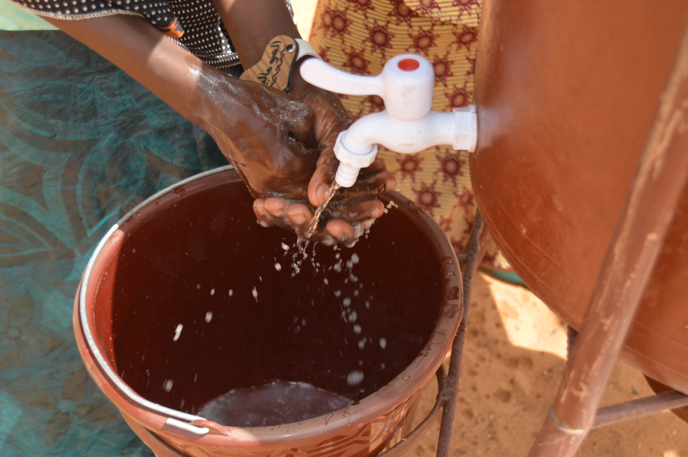 Ein Mädchen wascht sich Hände mit Wasser aus Kanister