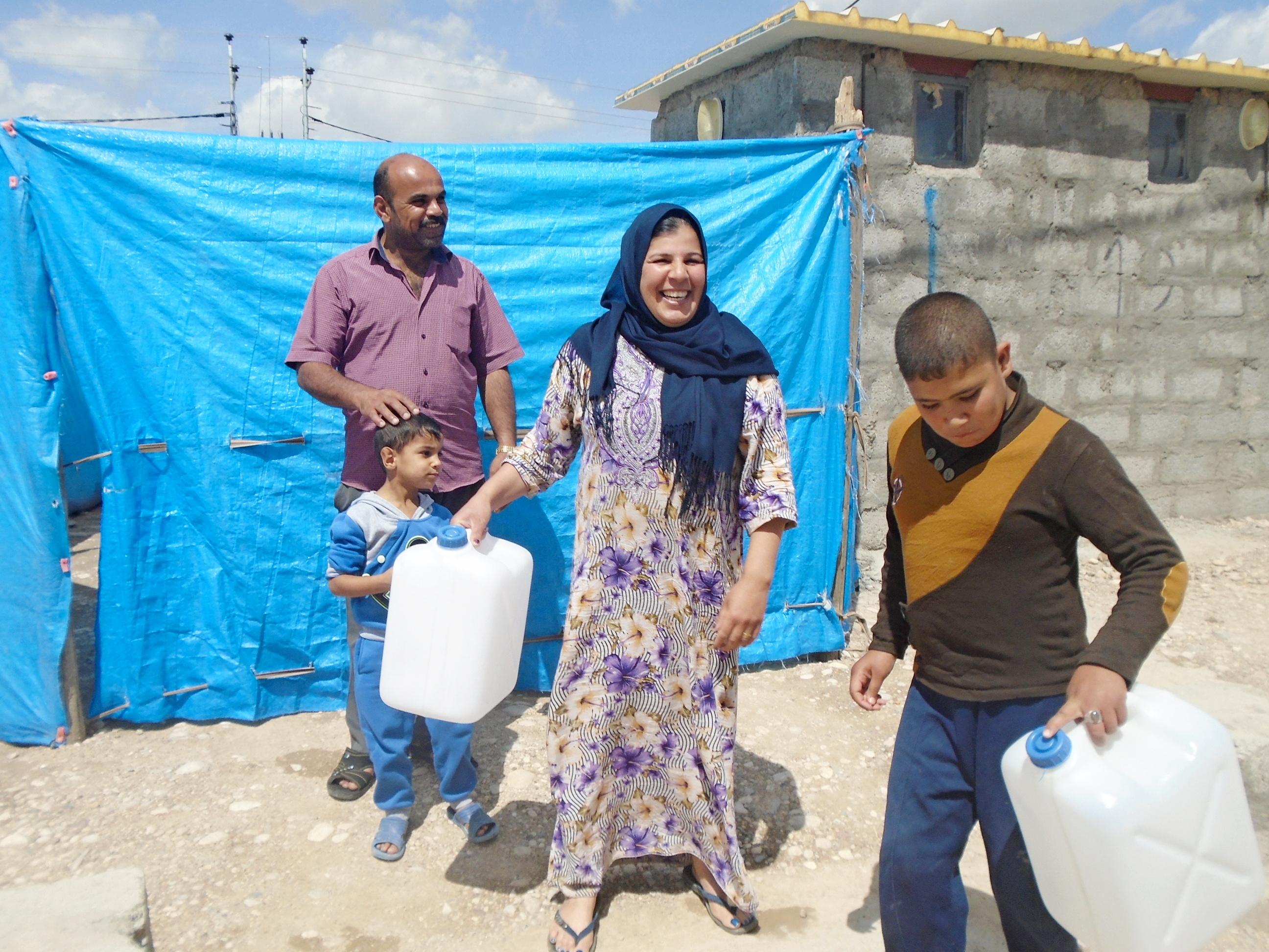Familie mit neuen Kanistern für ihr Wasser in der Notunterkunft