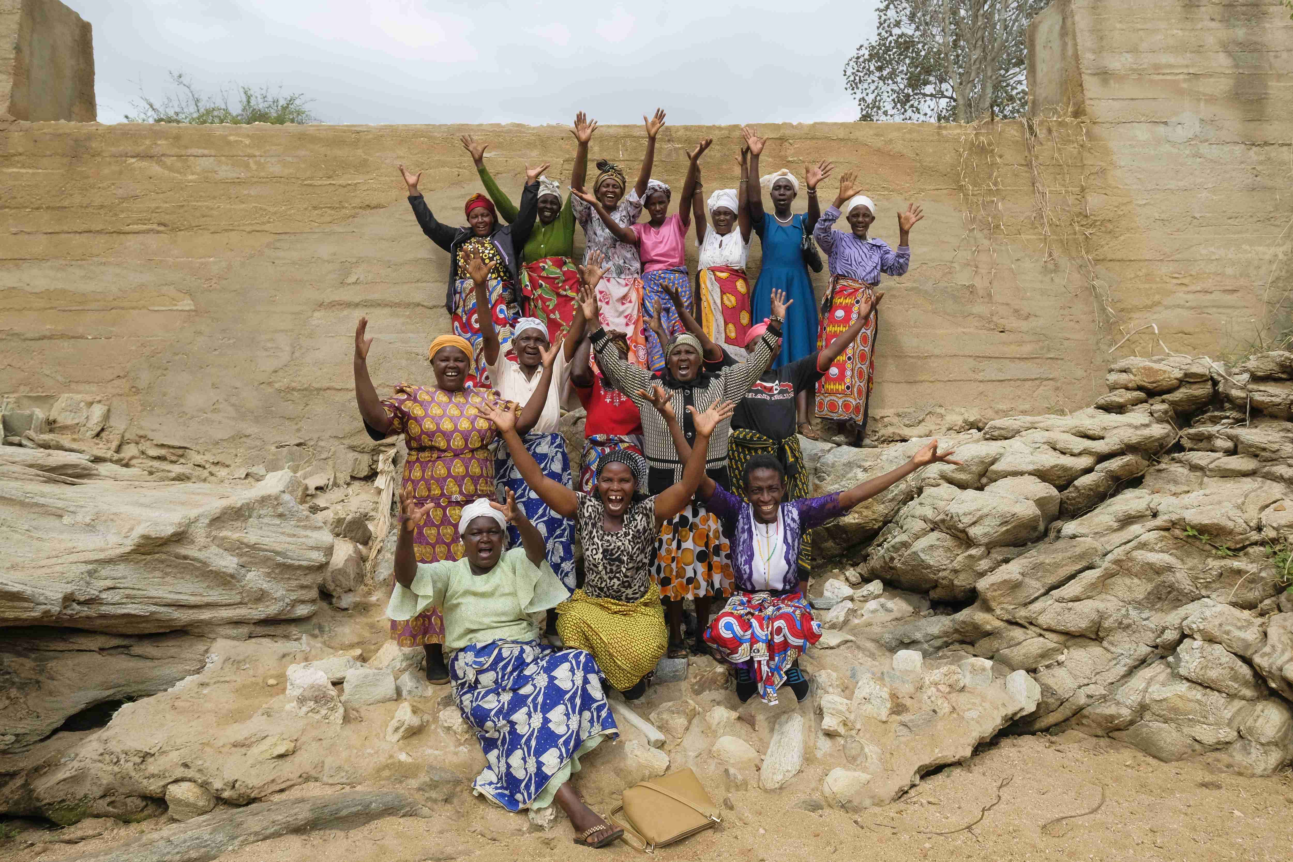 Rund ein Dutzend Frauen recken ihre Arme in die Höhe und lachen. Sie stehen und Hocken für das Gruppenbild vor der Betonmauer ihres Damms.