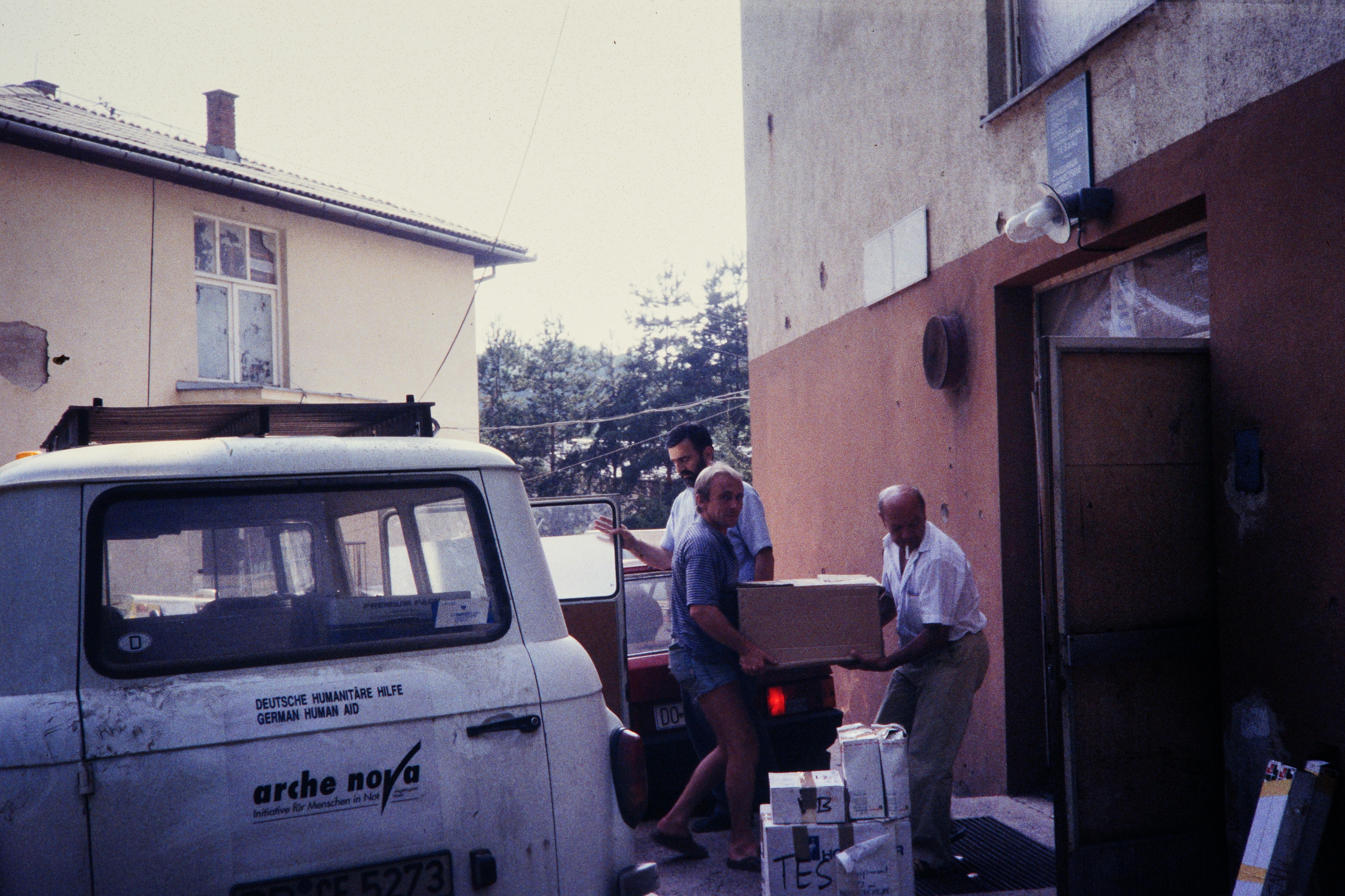 Männer tragen ein Paket von einem Barkas-Transport in ein Haus