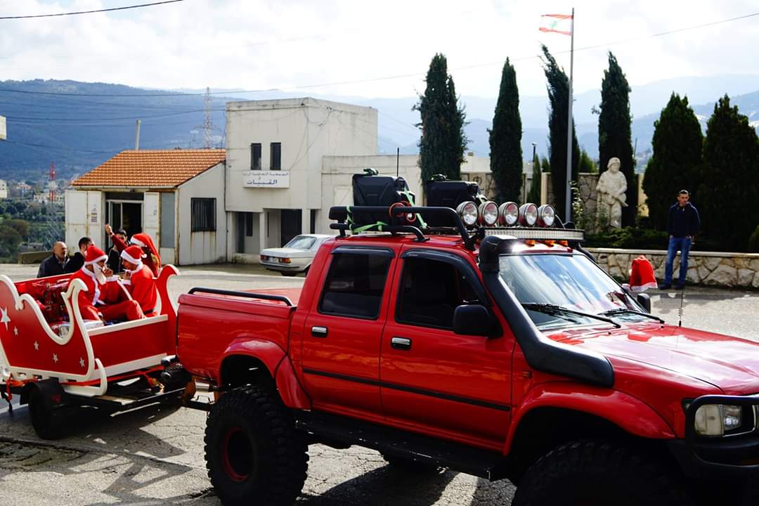 großer roter Truck zieht Schlitten mit 2 Weihnachtsmännern