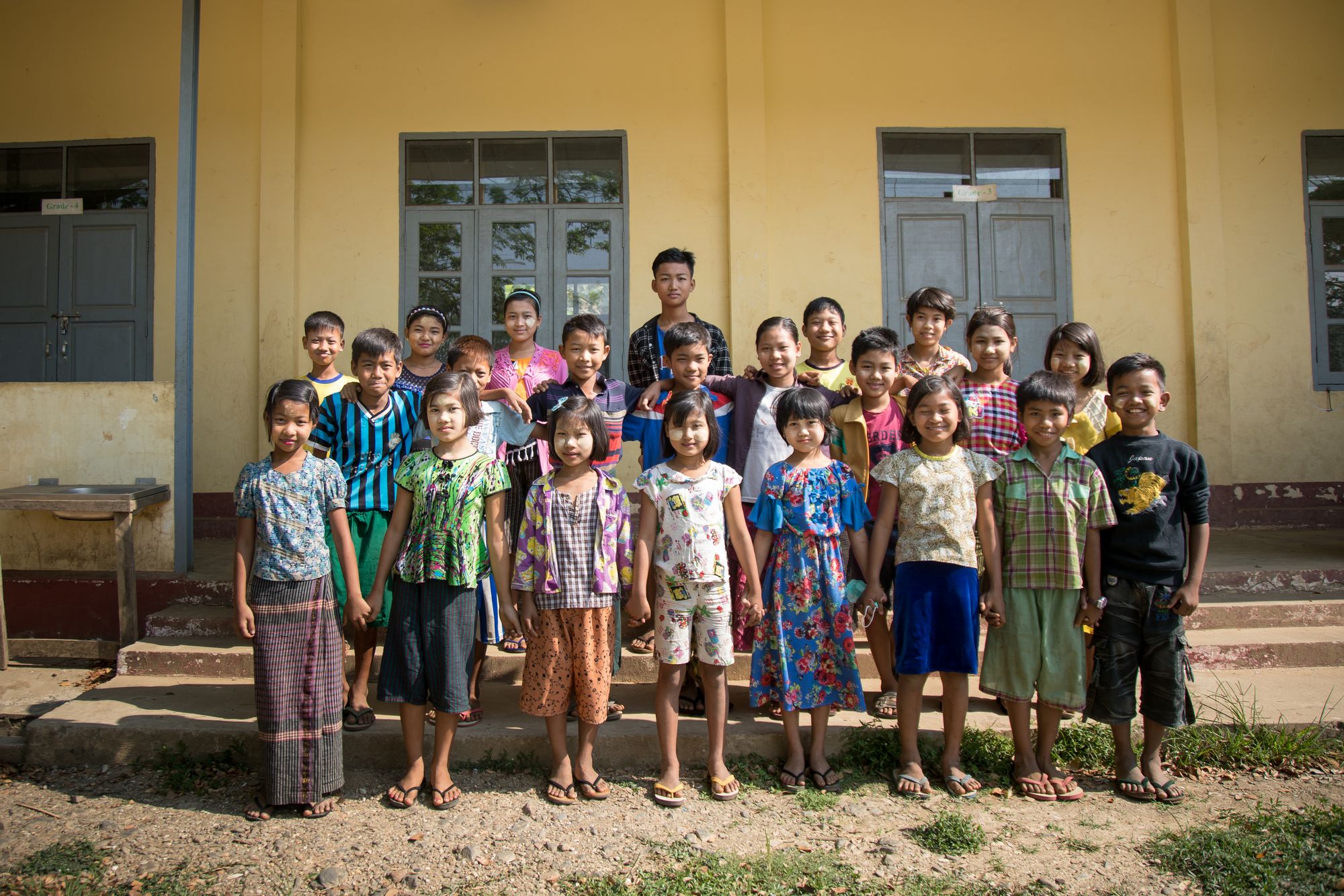 School class, standing in front of newly renovated school buildings 