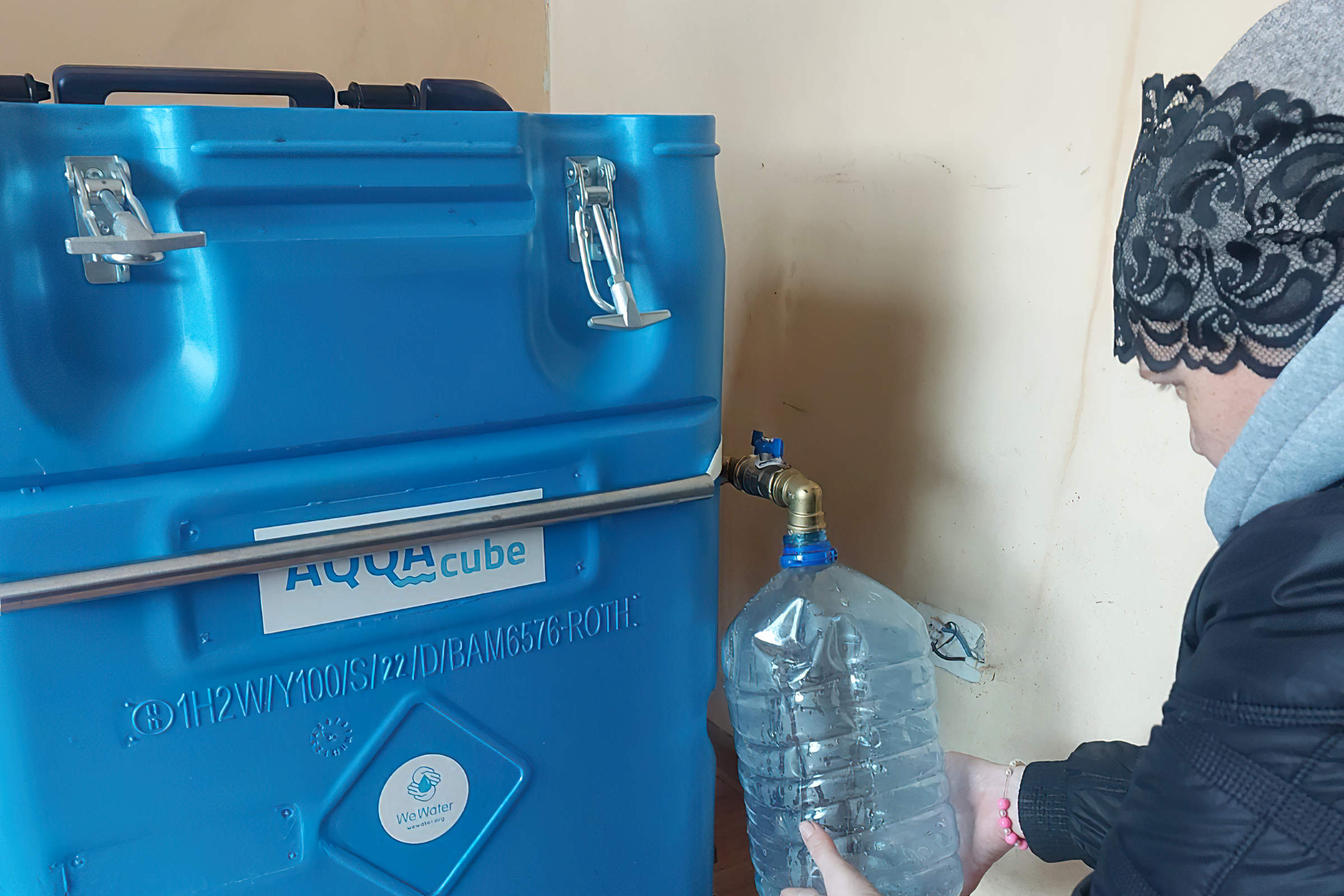 Frau füllt Wasser aus einem Filter in einen transparenten Wasserkanister