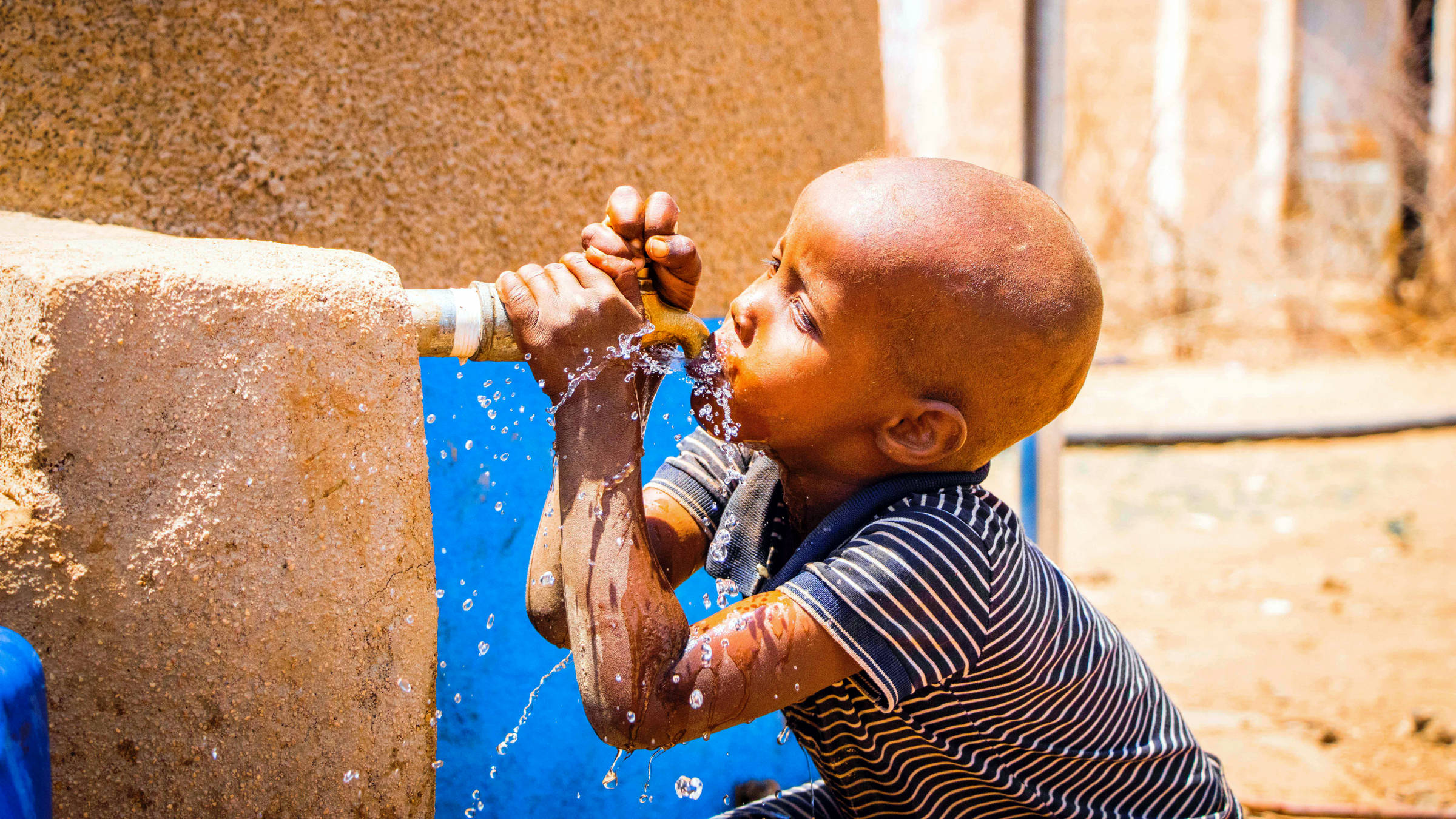 Kind trinkt Wasser aus einem Wasserhahn