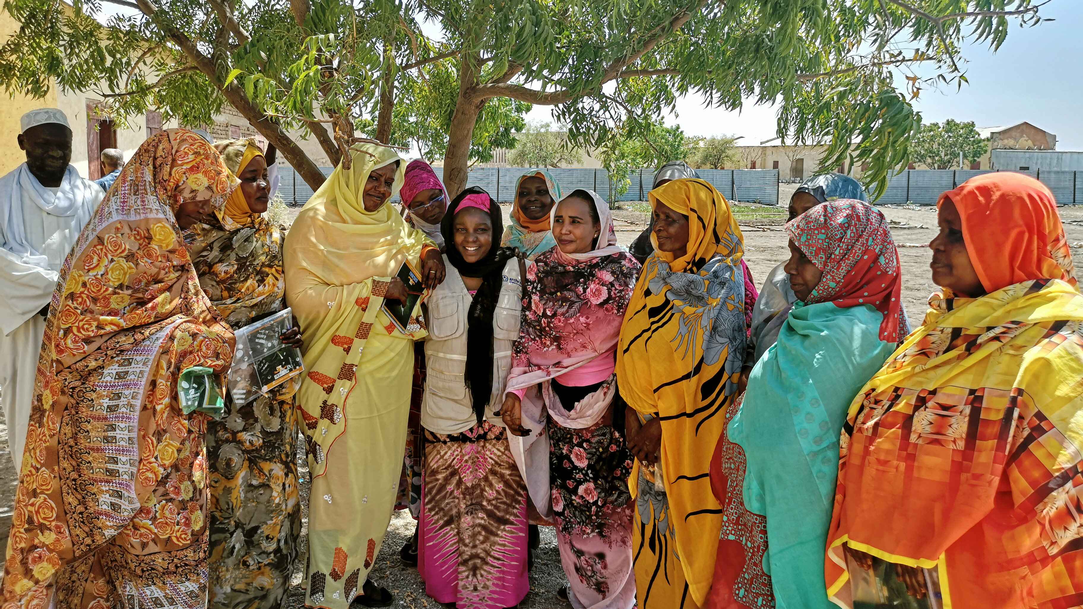 eine Gruppe bunt gekleiderter Frauen vor einem Baum
