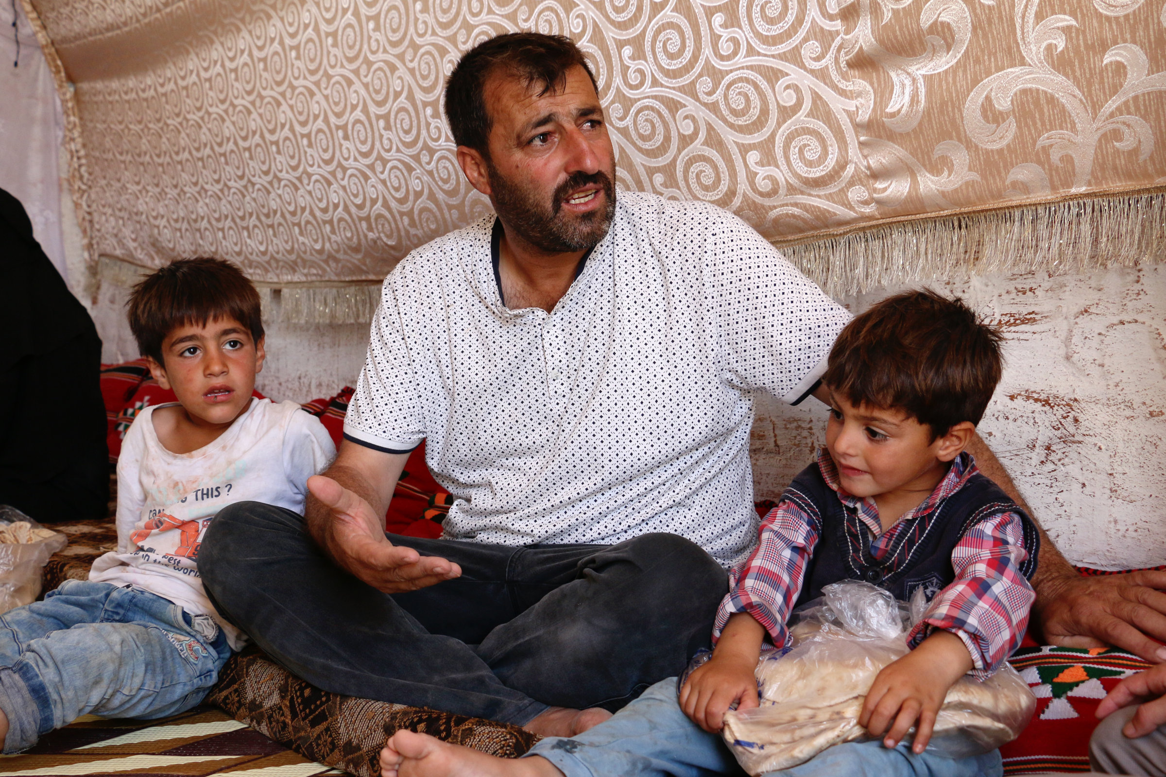 Das Bild zeigt Ahmed Hassan mit zwei seiner Söhne. Die Kinder sind ungefähr 4 und 7 Jahre alt. Das jüngere hält eine Tüte mit Brot in den Händen.