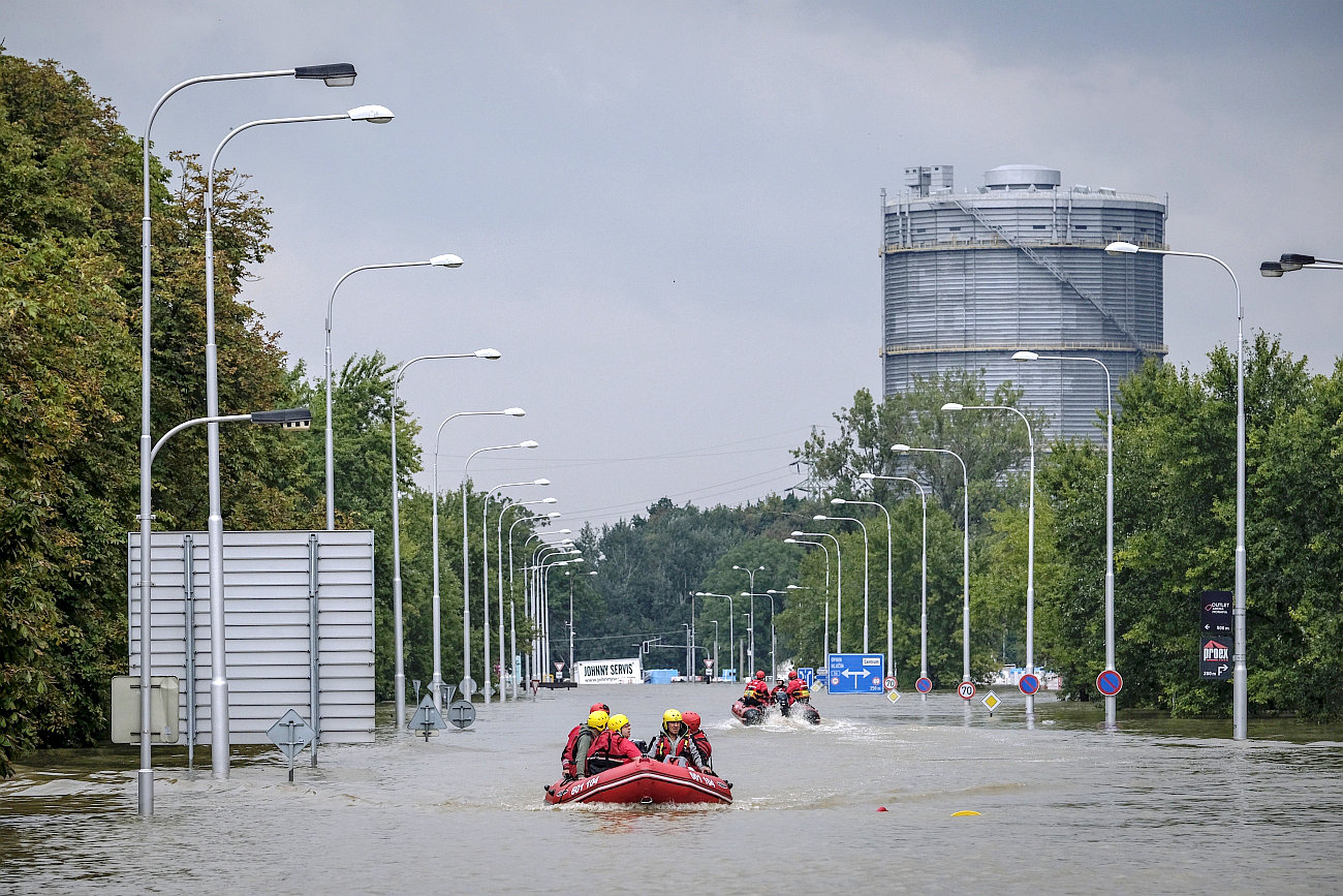 Eine von Wassermassen überflutete breite Straße, darauf zwei Schlauchboote mit Rettungskräften