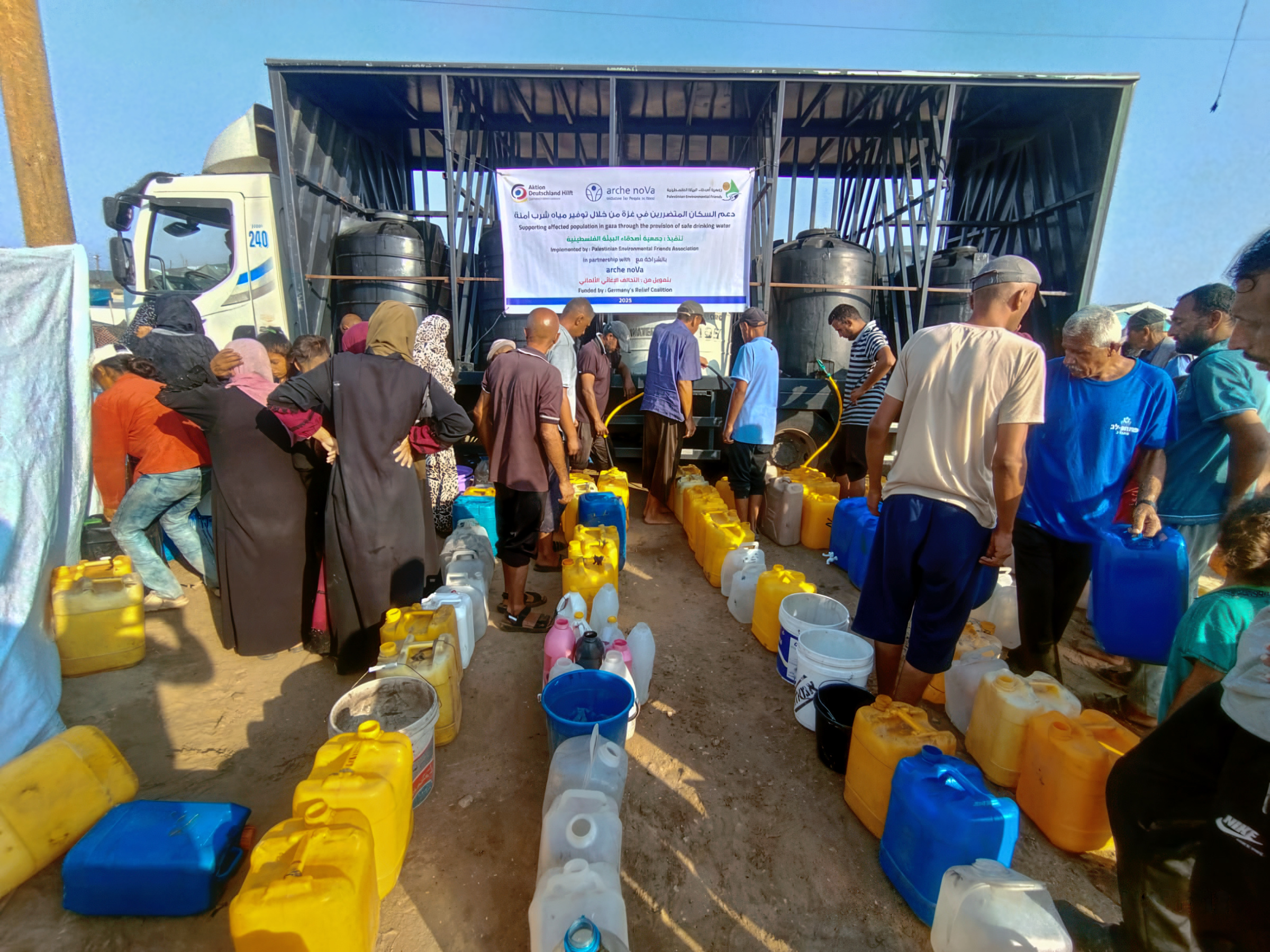 Menschne stehen an einer Wasserausgabestelle an