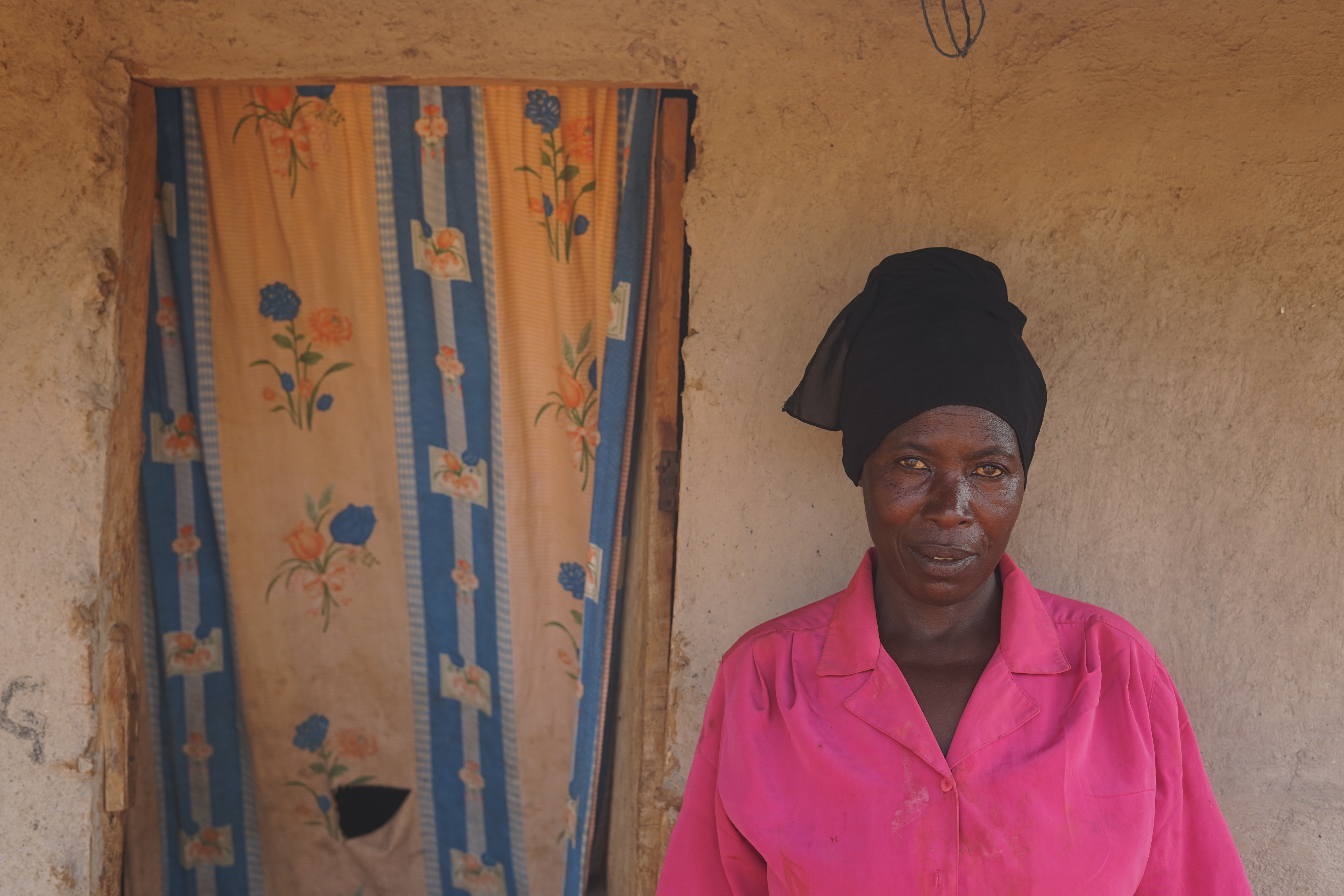 Frau vor Wand eines Gebäudes, neben ihr ein Vorhang