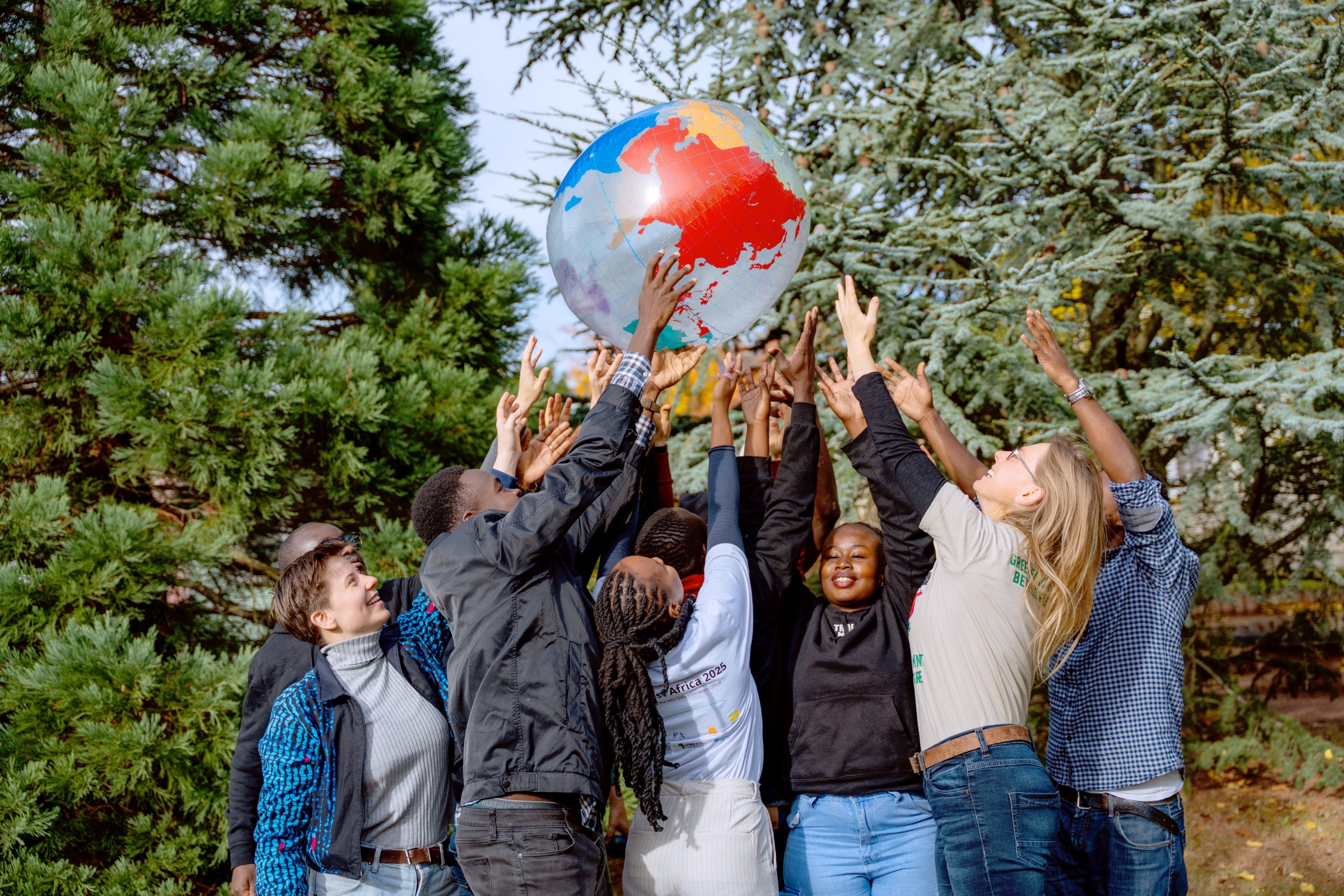 eine Gruppe Menschen balanciert gemeinschaftlich einen Erdkugel-Wasserball
