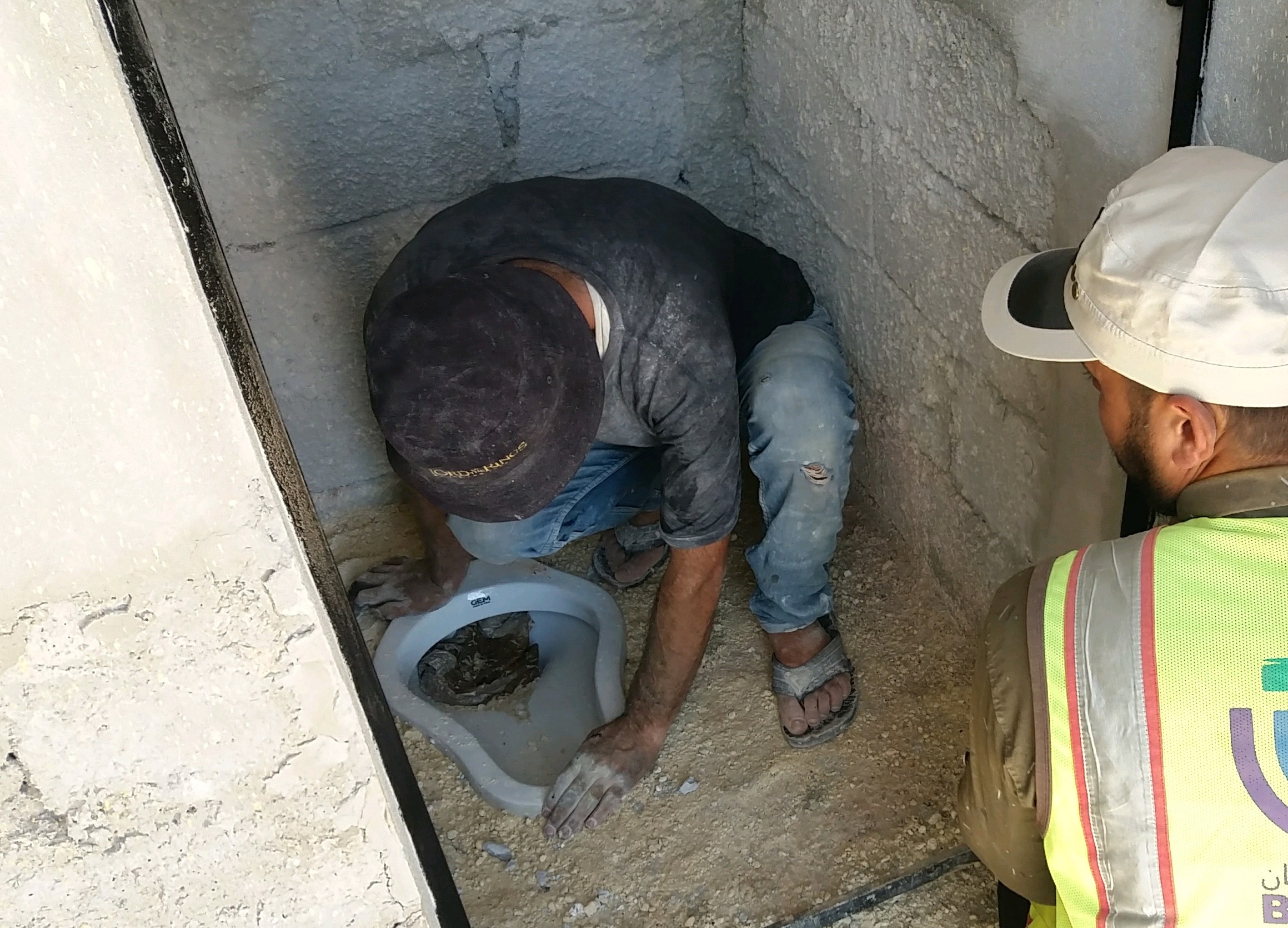 Blick in eine Toilettenkabine Bauarbeiter installieren einen Abtritt