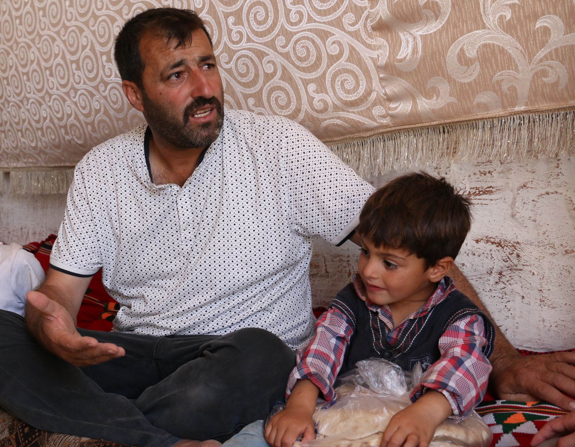 Das Bild zeigt Ahmed Hassan mit einem seiner Söhne. Das Kind ist ungefähr 4 Jahre alt und hält eine Tüte mit Brot in den Händen.