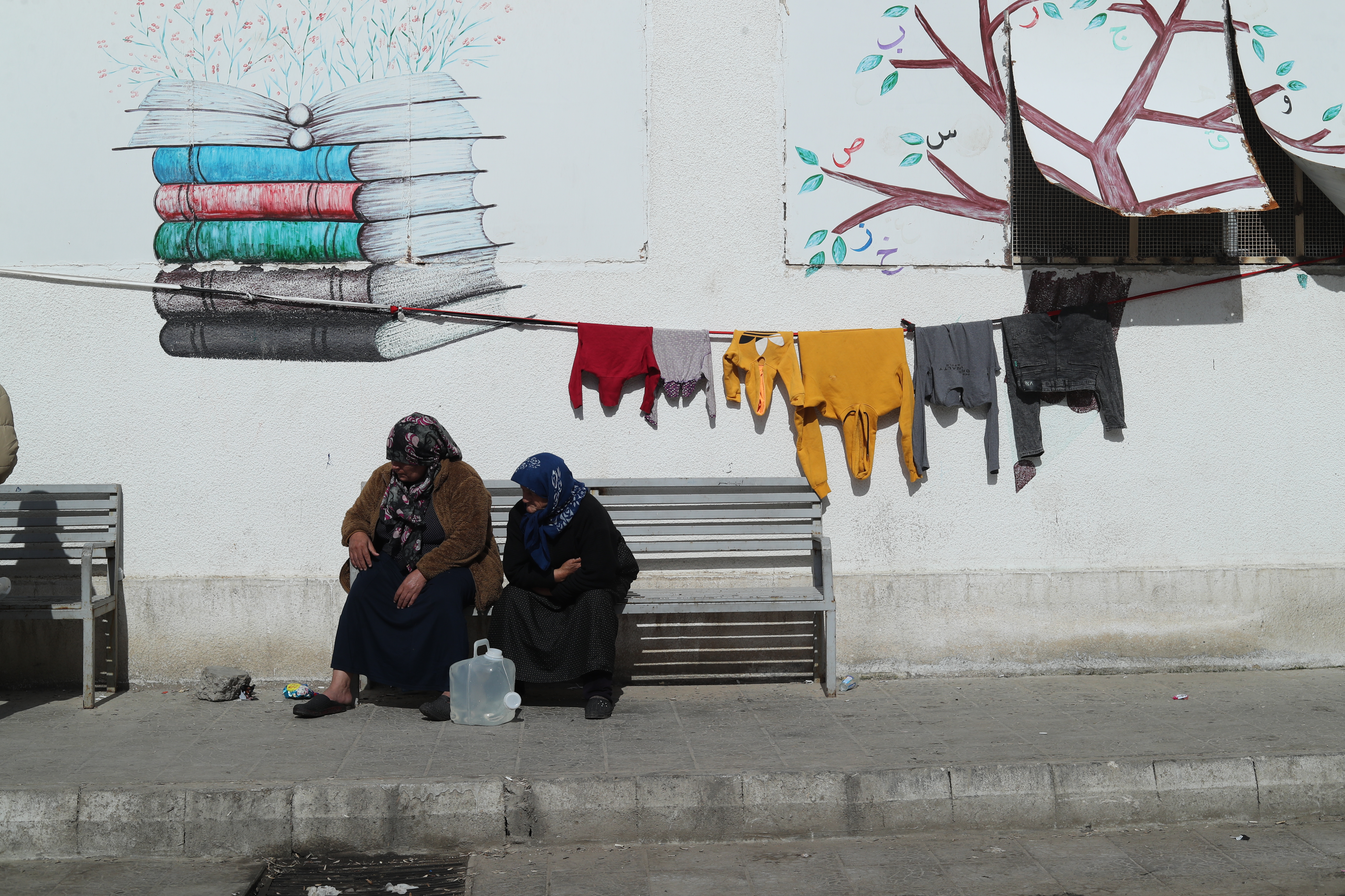 Zwei ältere Frauen sitzen auf einer Bank vor einer Hauswand