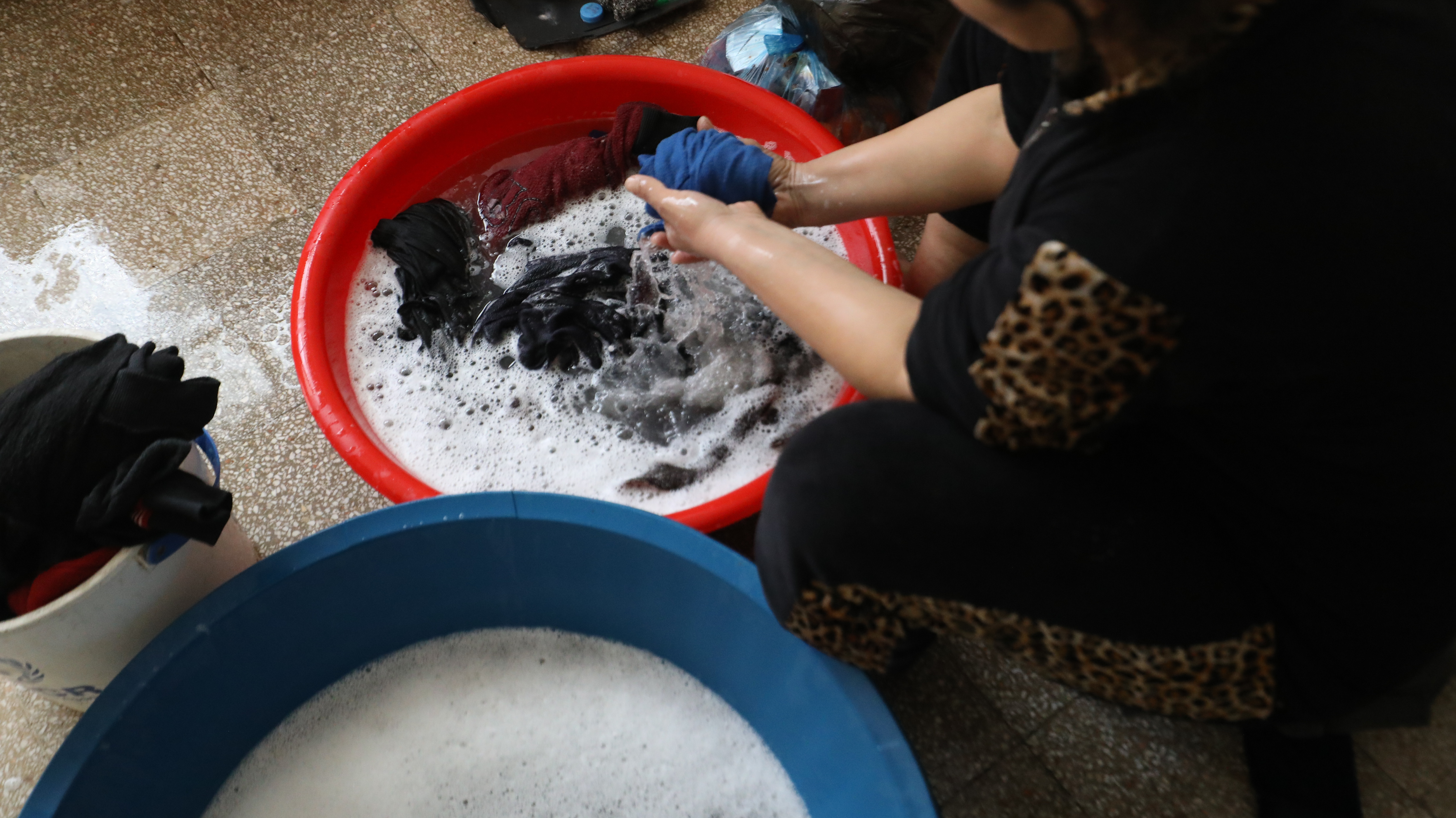 Nahaufnahme einer Waschschüssel mit Händen, die Wäsche waschen