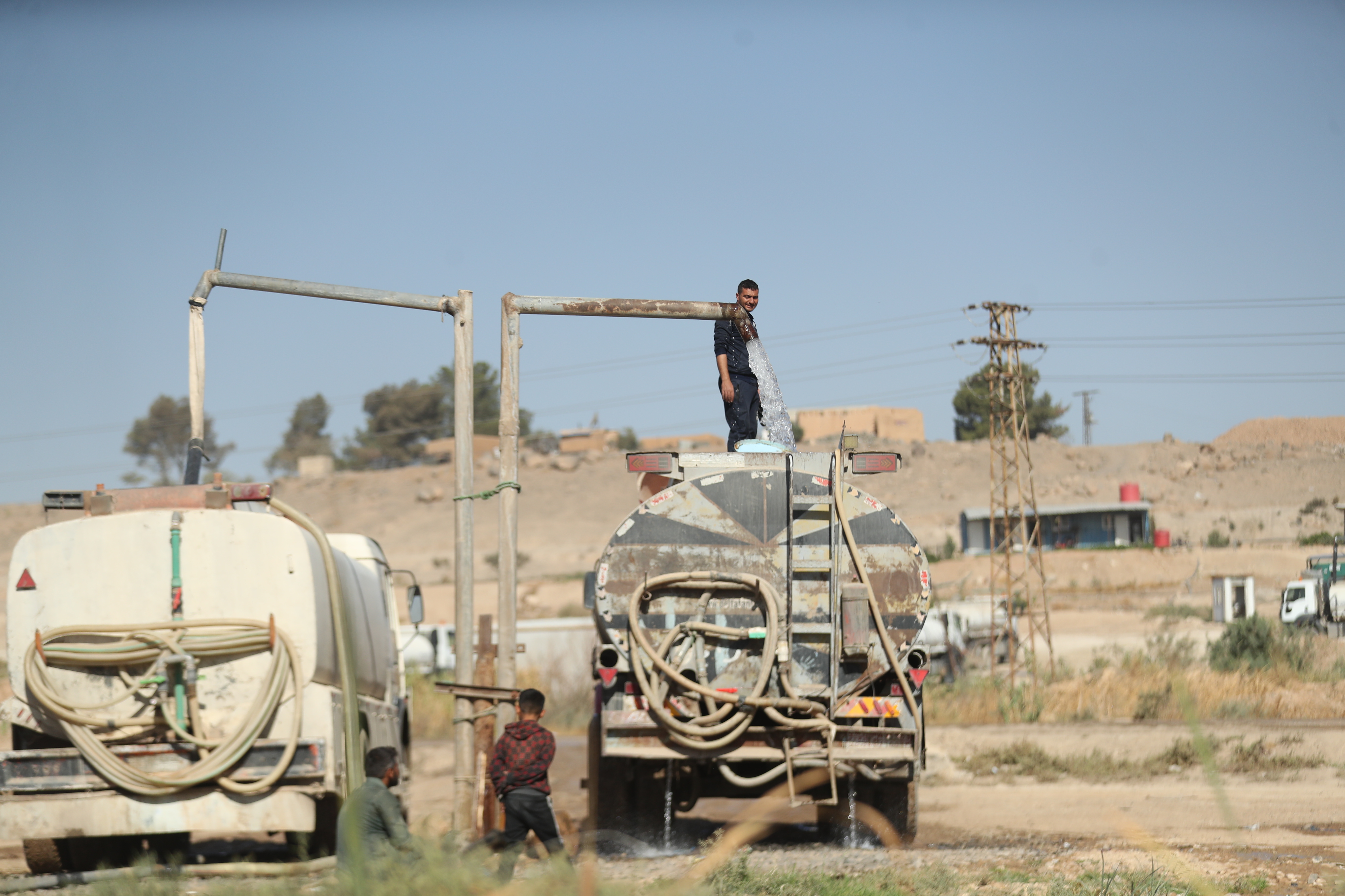 Zwei Tanklaster von hinten, darüber eine Konstruktion mit dicken Schläuchen zum Befüllen