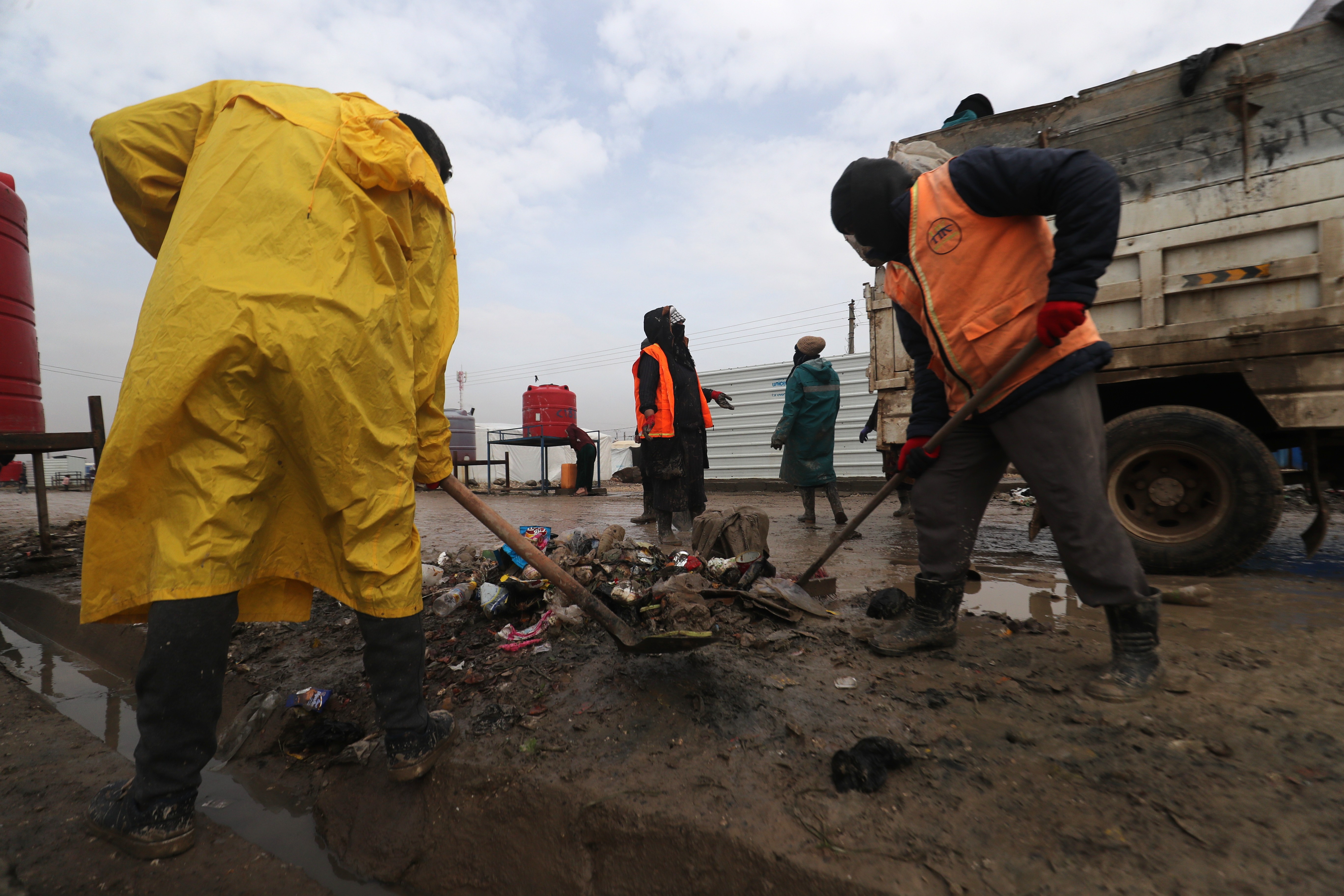 zwei Personen schaufeln Müll auf