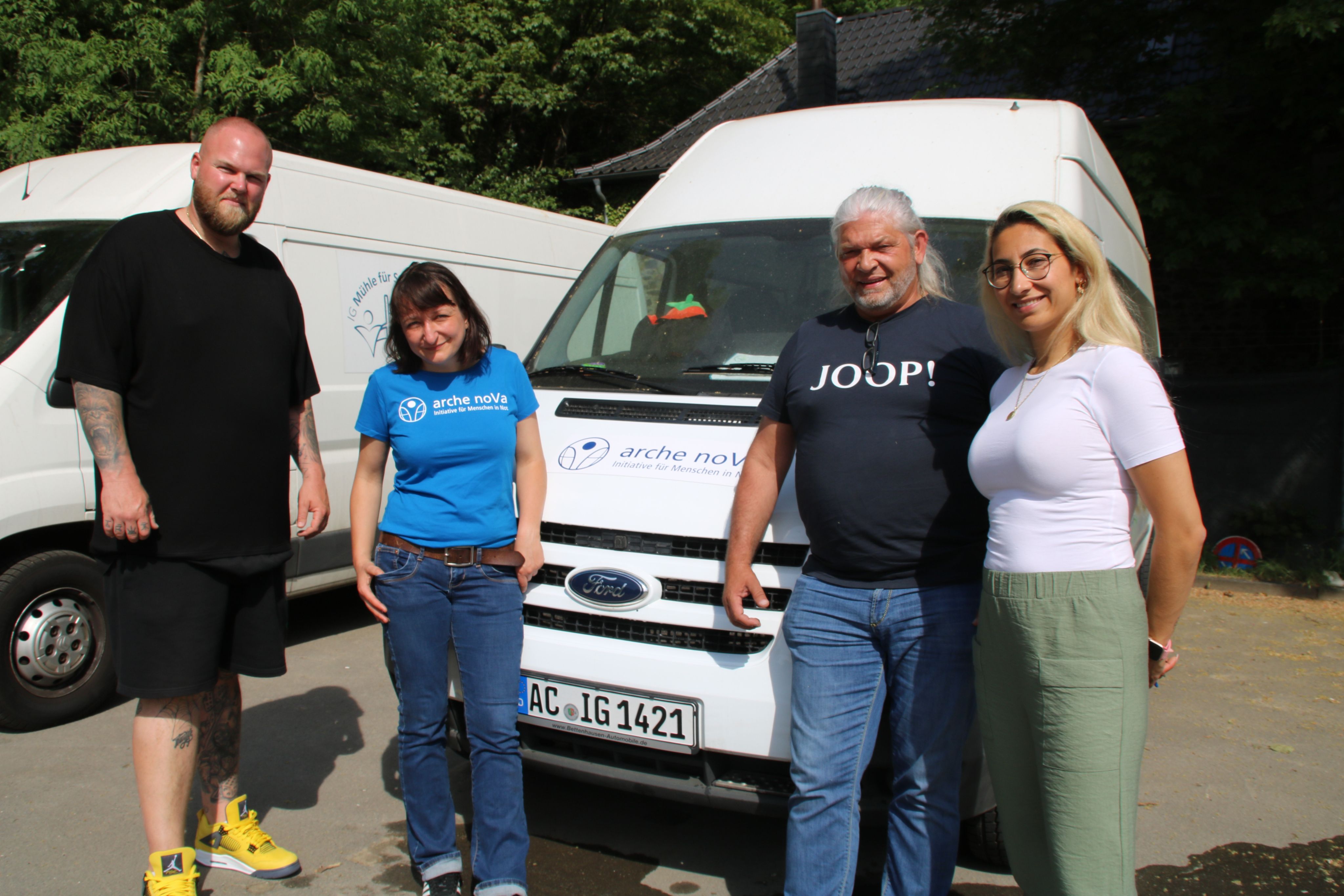 Anke Bartz, Projektleiterin Hochwasserhilfe bei arche noVa, und drei Mitglieder des Vereins IG Mühle für Stolberg. Hinter der Gruppe steht ein weißer Lieferwagen, auf dessen Motorhaube das Logo von arche noVa zu sehen ist.