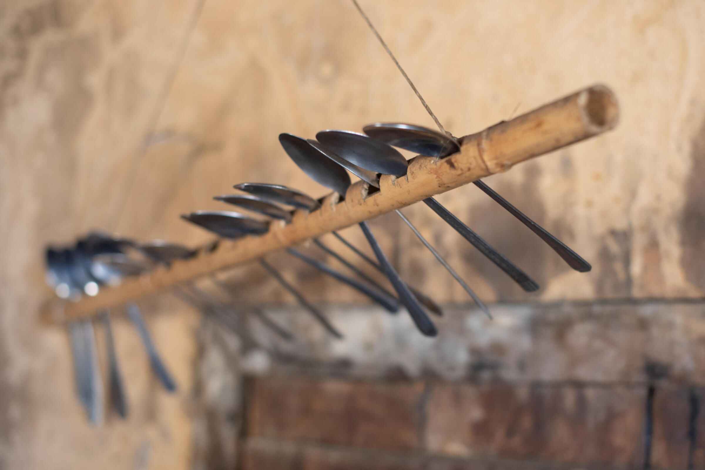 Eine Art Bambusstab, in welchen Löcher gemacht wurden. In den Löchern stecken Löffel. Der Stab ist an der Decke befestigt.