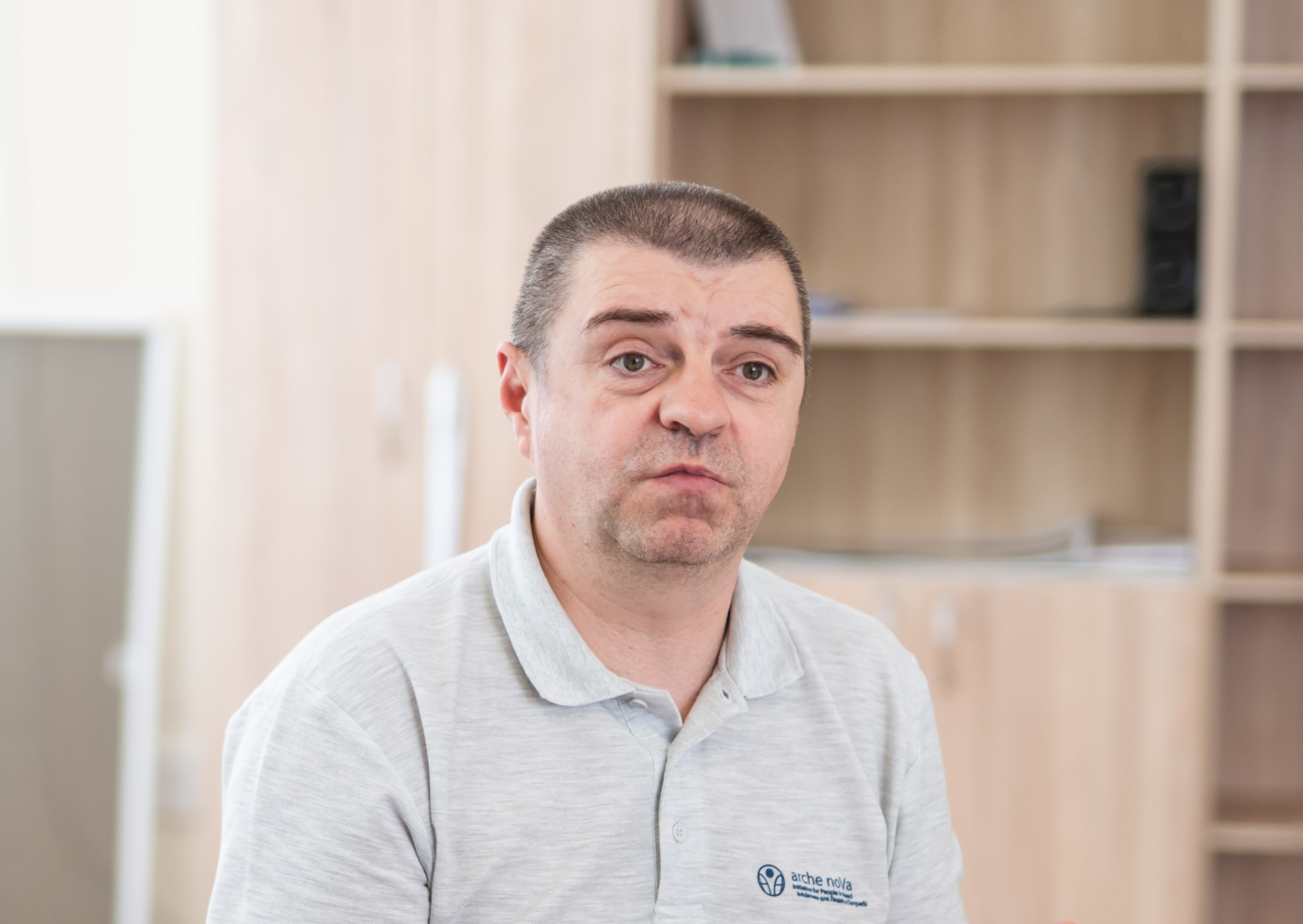 Das Foto zeigt einen Mann mittleren Alters mit kurzem Haar im Polo-Shirt. Im Hintergrund ist ein Büroraum mit Bücherregalen zu sehen.
