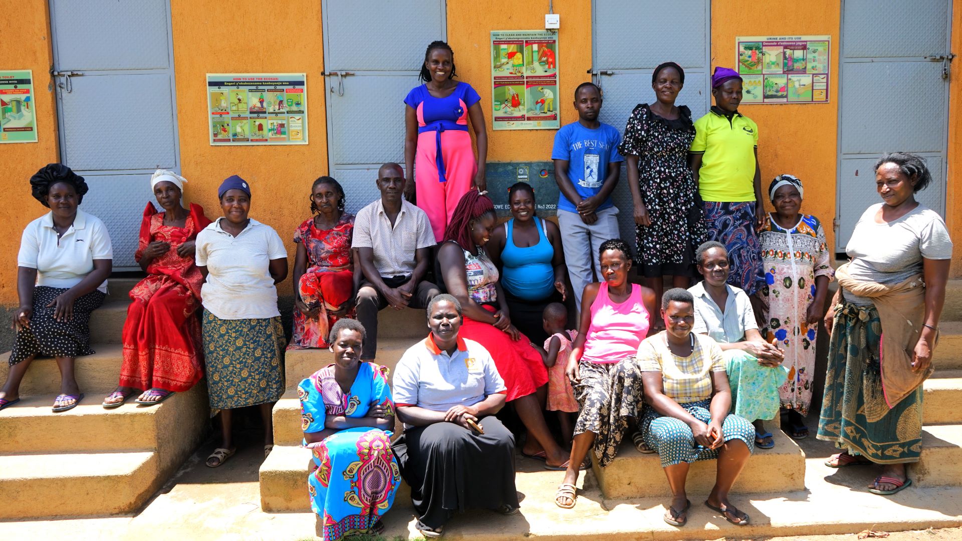 Eine Gruppe von Frauen steht bzw. sitzt vor einem Gebäude mit sanitären Anlagen