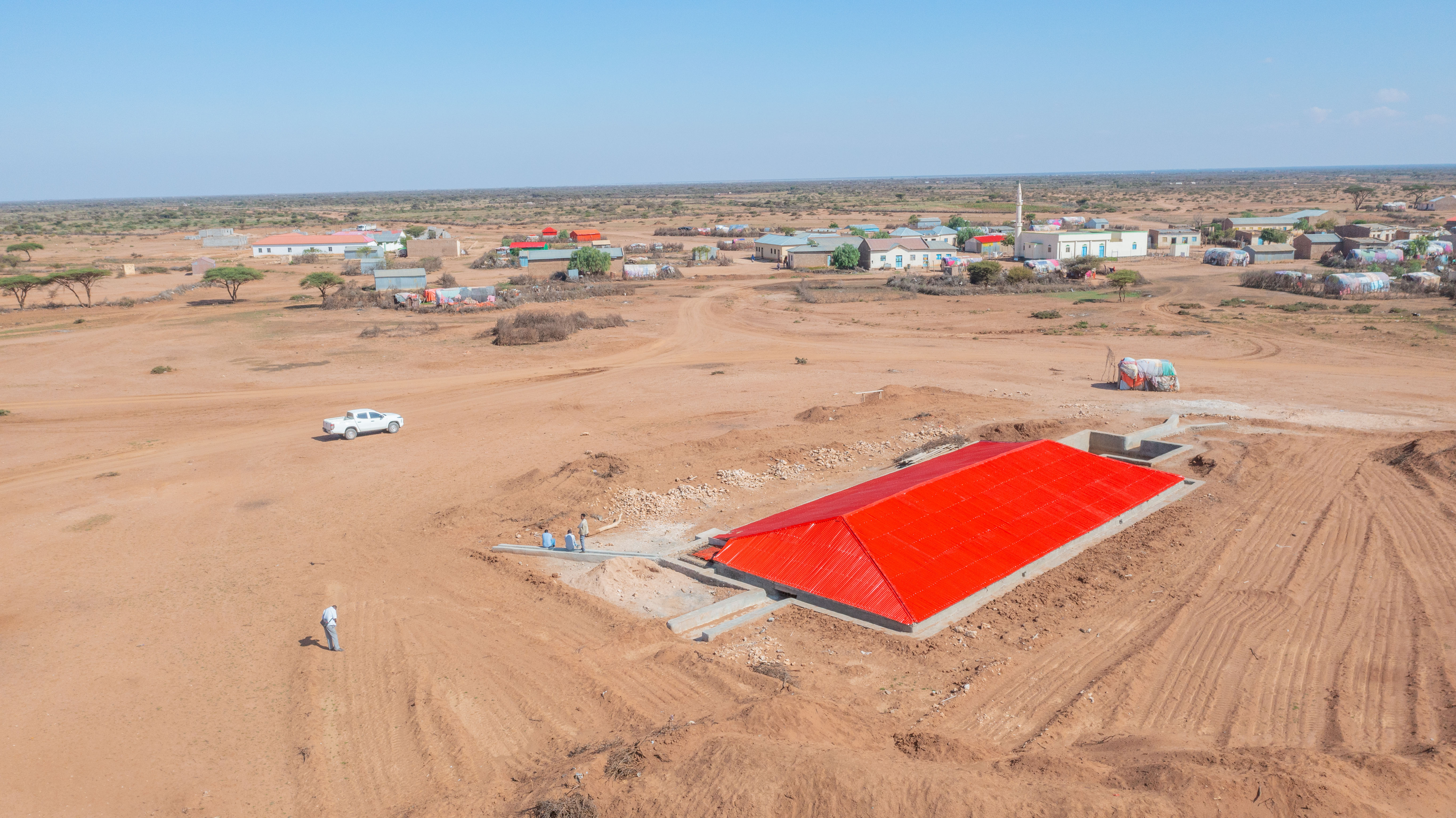 Luftaufname eines Birka Wasserspeichers, man sieht das rot leuchtende Wellblechdach von oben