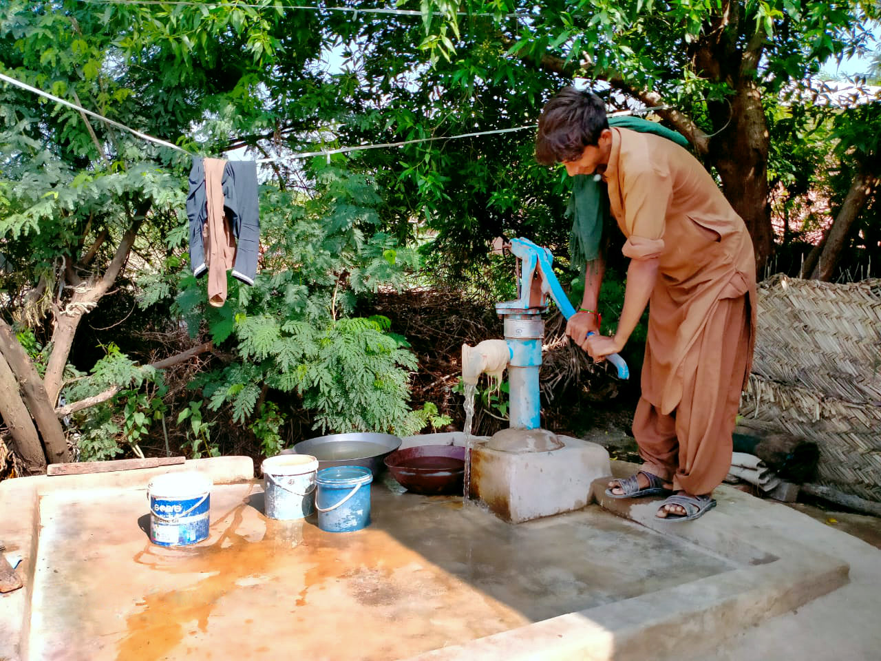 Mann pumpt Wasser an Handpumpe
