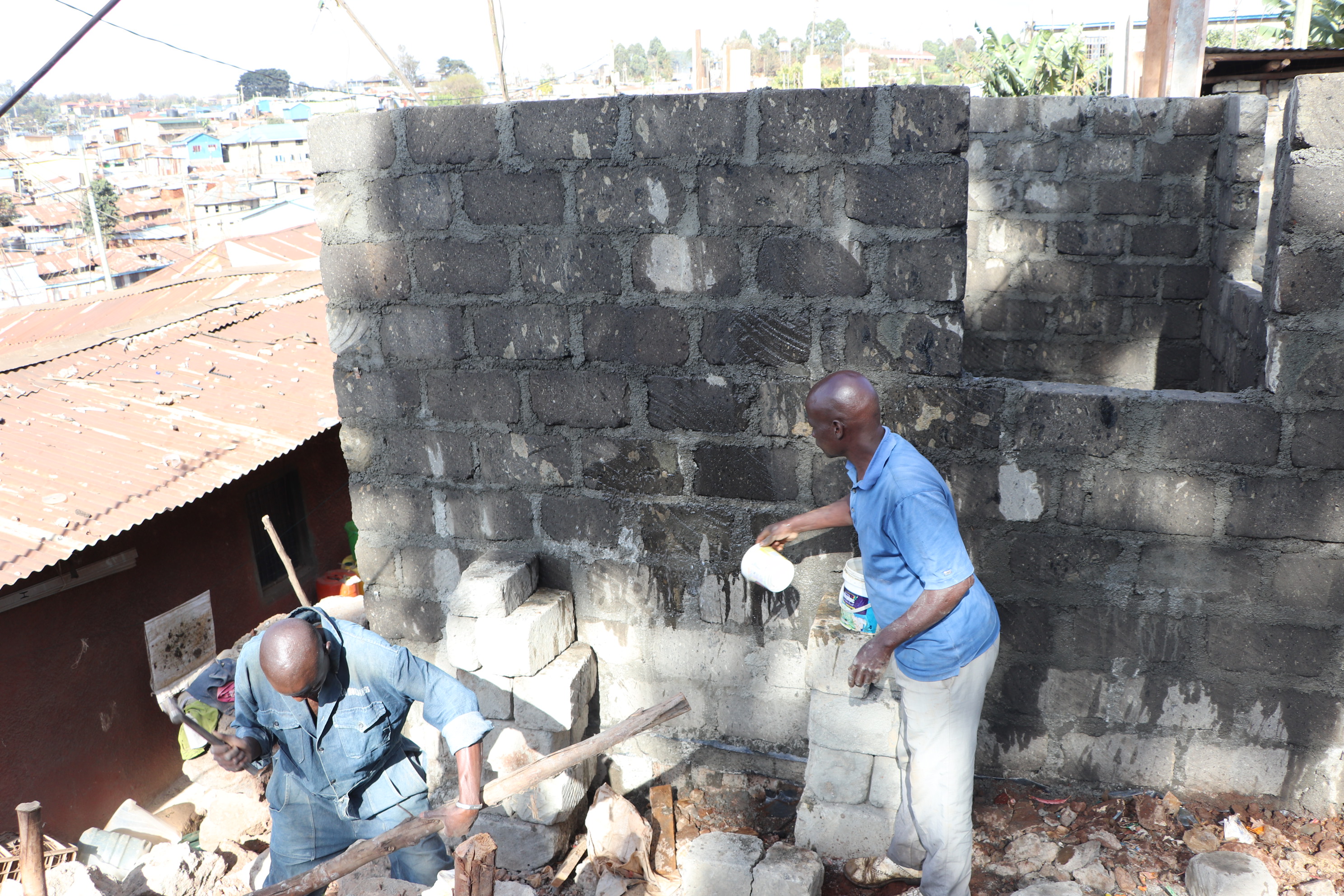 Zwei Männer arbeiten vor einer neu gebauten Mauer