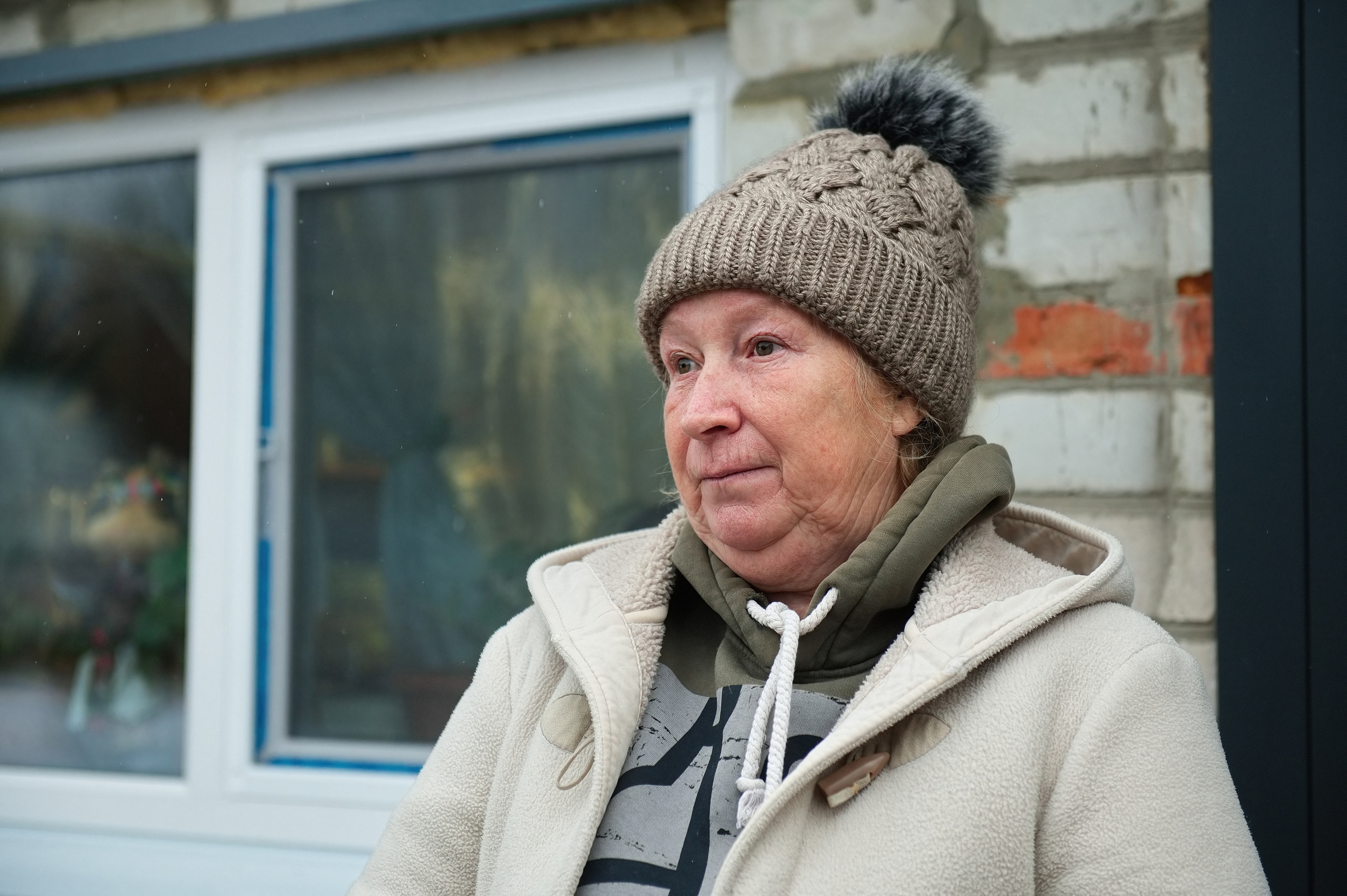 Lyobov Demeshko, eine 63-Jährige Rentnerin aus Staryj Saltiw, steht vor ihrem Haus. Im Hintergrund sind die neuen Fenster des Hauses zu sehen.