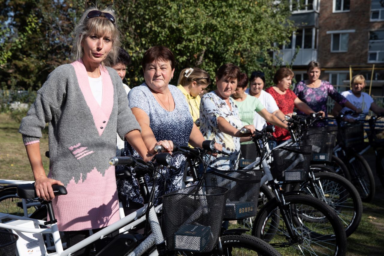 The picture shows the employees of the Okhtyrka Municipal Center of Social Service. The electric bicycles they received from arche noVa are standing beside them.
