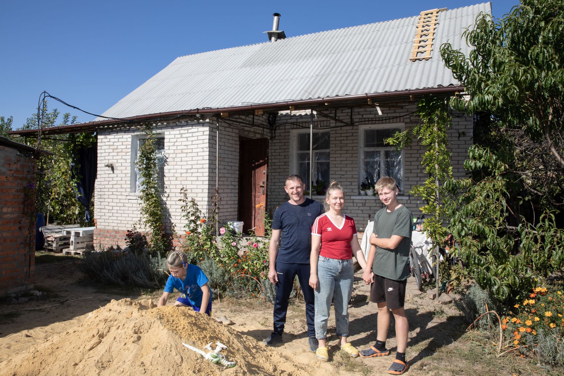 Familie Novytska steht vor ihrem Haus in Staryj Saltiw, das während der russischen Invasion schwer beschädigt wurde.