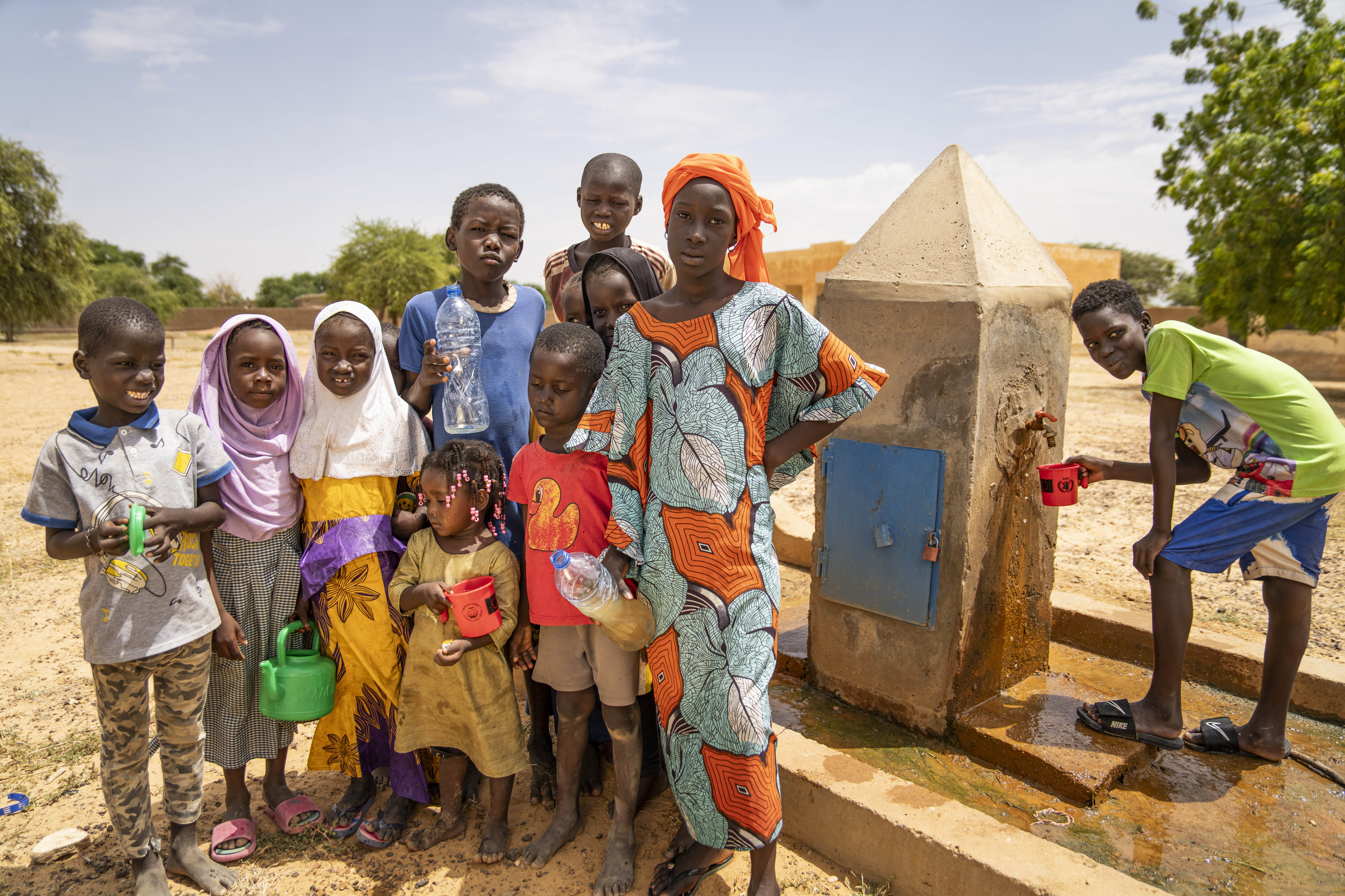 Das Foto zeigt eine Gruppe von Kindern unterschiedlichen Alters vor einer Wasserentnahmestation.