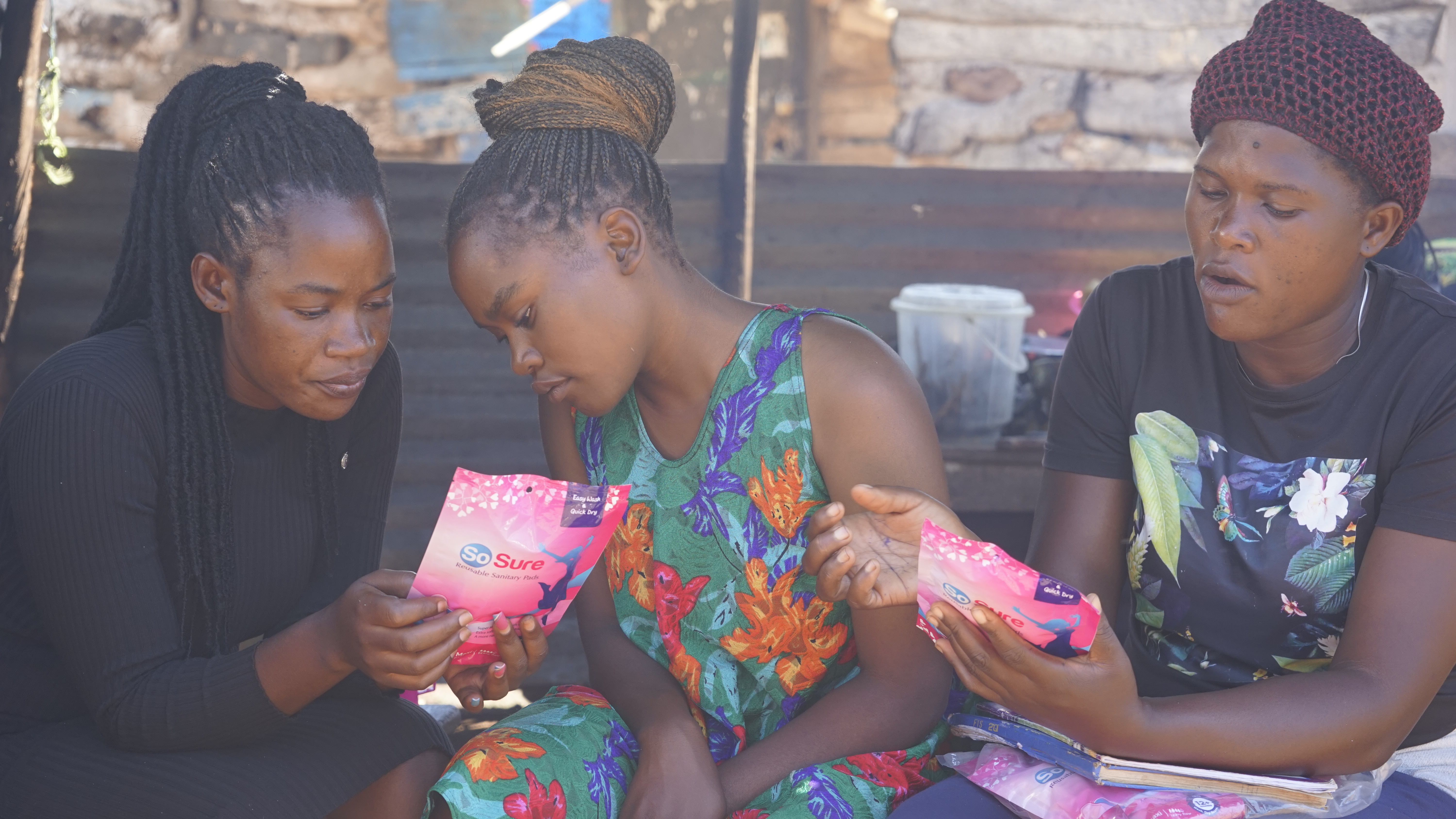 Drei Frauen, zwei von ihnen halte Menstruationsprodukte in der Hand