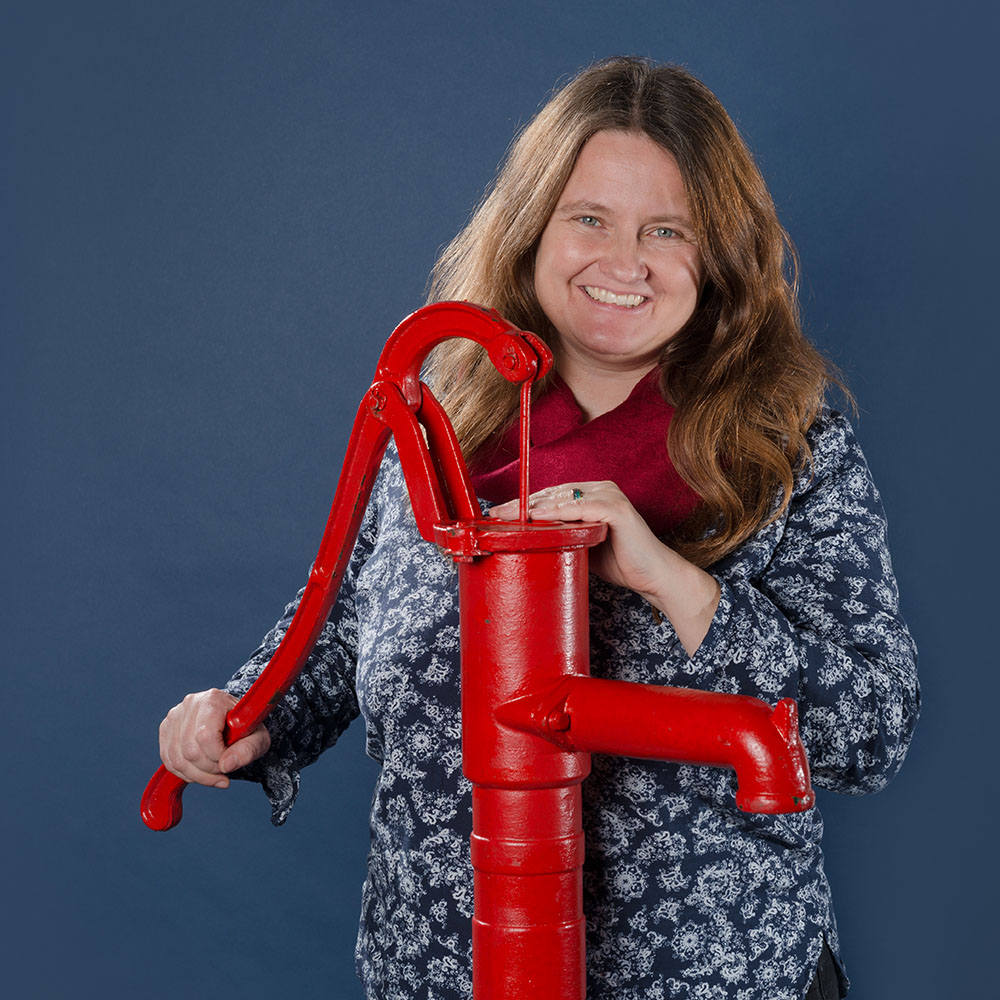 Portrait Andrea Bindel mit roter Handpumpe