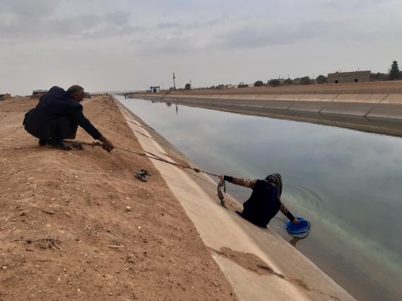 Eine Frau seilt sich zu einem Kanal ab, um Wasser zu holen