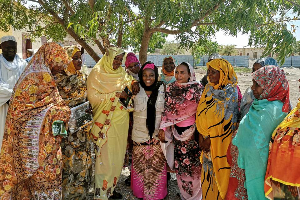 eine Gruppe bunt gekleiderter Frauen vor einem Baum